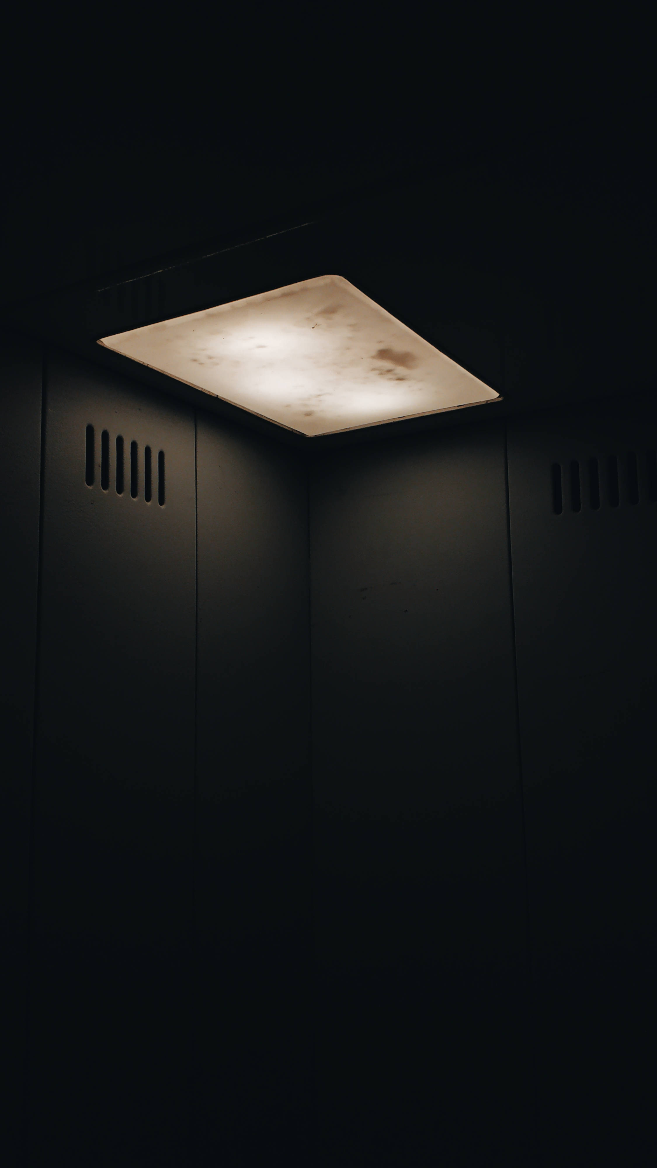 Dim 桌布 壁紙 — 一個正方形的天花板燈在有通風牆的黑暗封閉空間中發出溫暖的光芒。