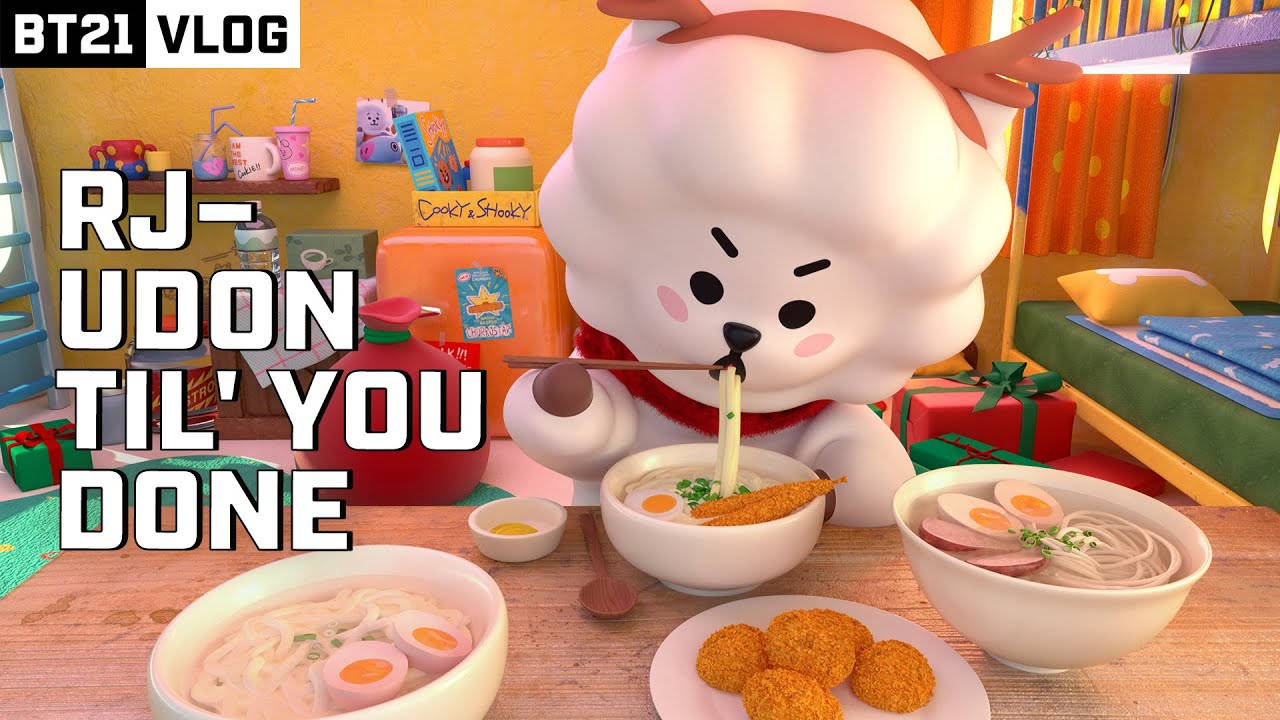 rj bt21 桌布 壁紙 — 一個毛茸茸的白色卡通角色，長有鹿角，在色彩繽紛的桌子旁吃烏冬麵，周圍擺滿了食物碗和禮物。