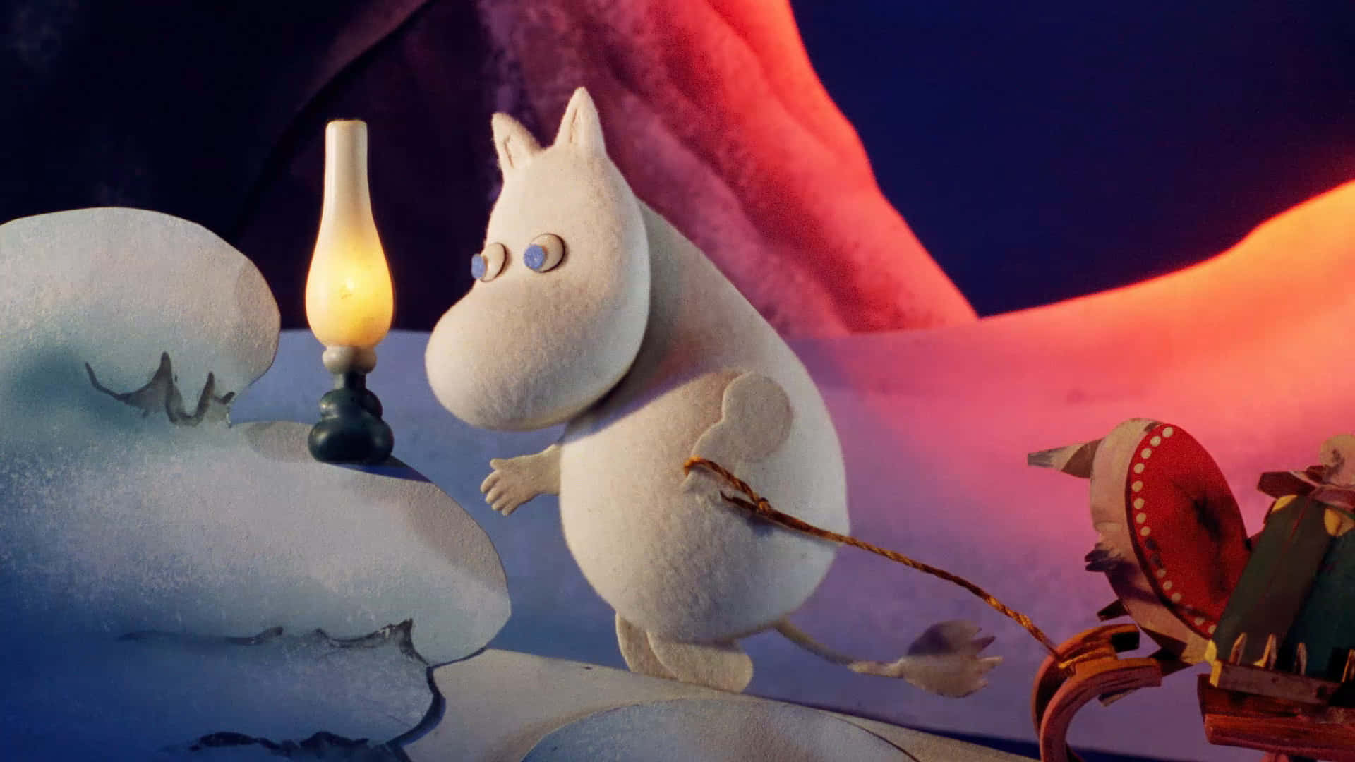 Moomin Desktop 桌布 壁紙 — 一個毛茸茸的白色姆明角色站在一個發光的油燈旁邊，在一個有溫暖橙色和藍色照明的雪洞中。