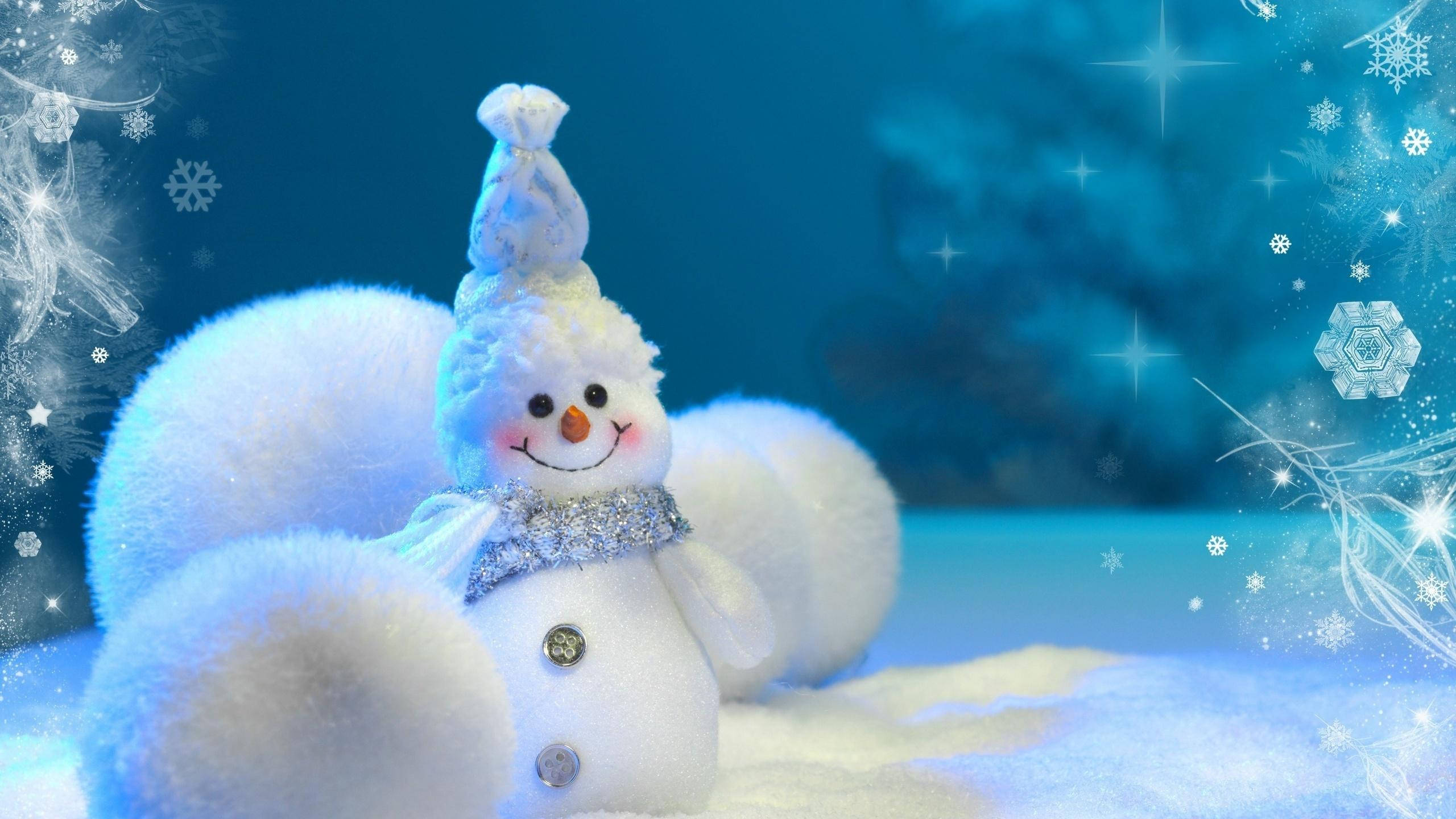 Cute Snow 桌布 壁紙 — 一個毛茸茸的雪人，戴著閃閃發光的圍巾和帽子，坐在白雪皚皚的藍色冬季仙境中，有閃爍的星星和雪花。