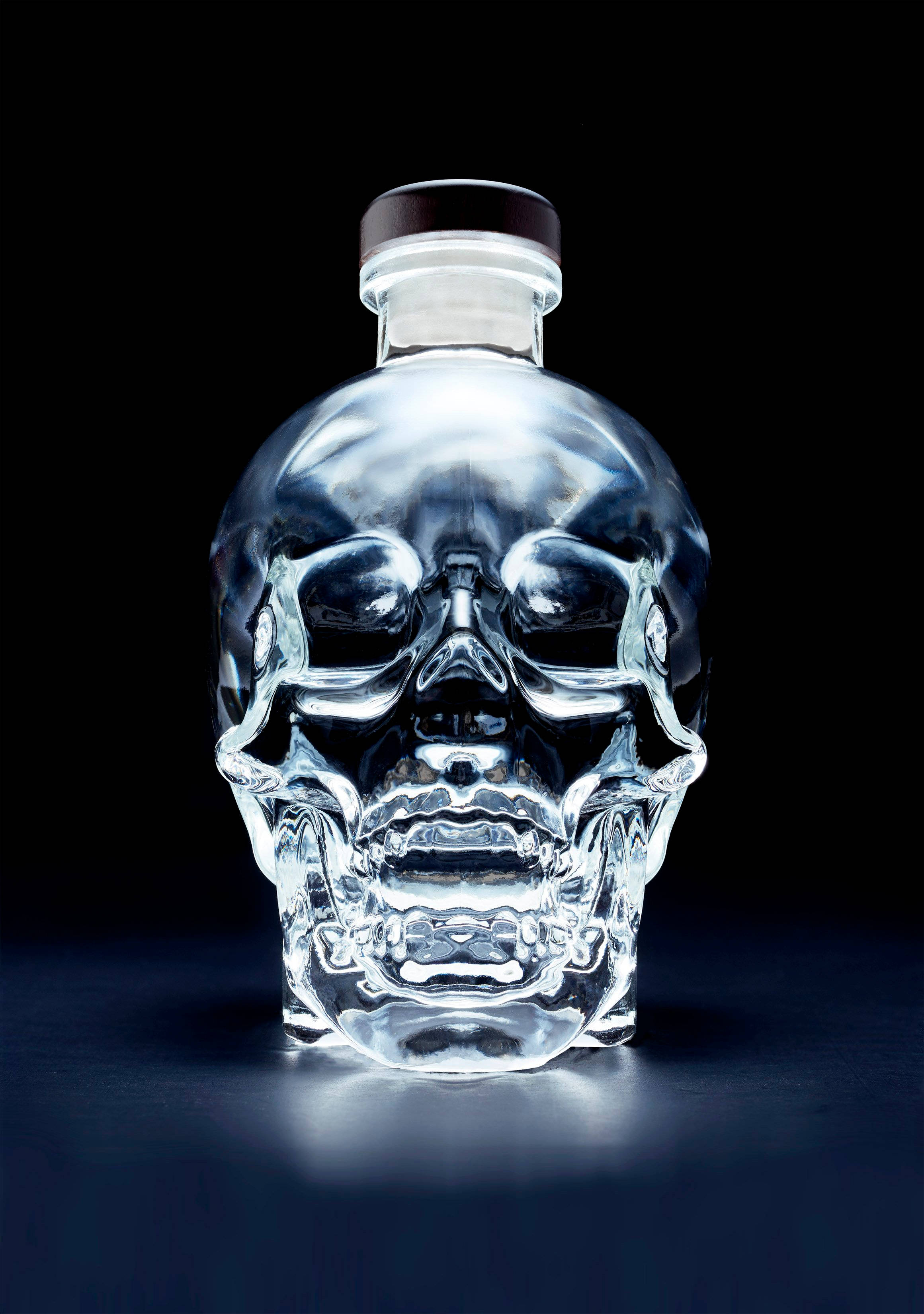 Drink 桌布 壁紙 — 一個水晶骷髏形狀的伏特加酒瓶在攝影棚燈光下，在純黑背景上閃閃發光。