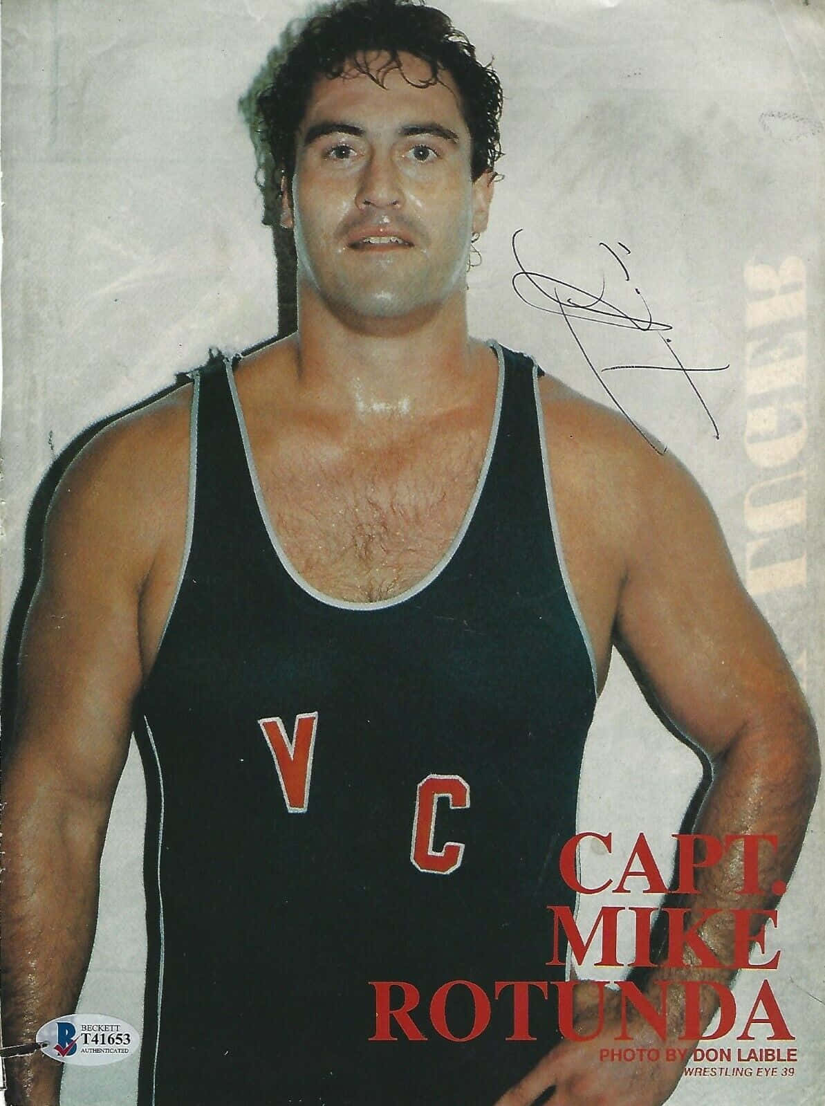 WWE 桌布 壁紙 — 一個汗流浹背、肌肉發達的摔角手，身穿帶有紅色V C字母的黑色緊身衣，在純色背景下凝視著鏡頭。