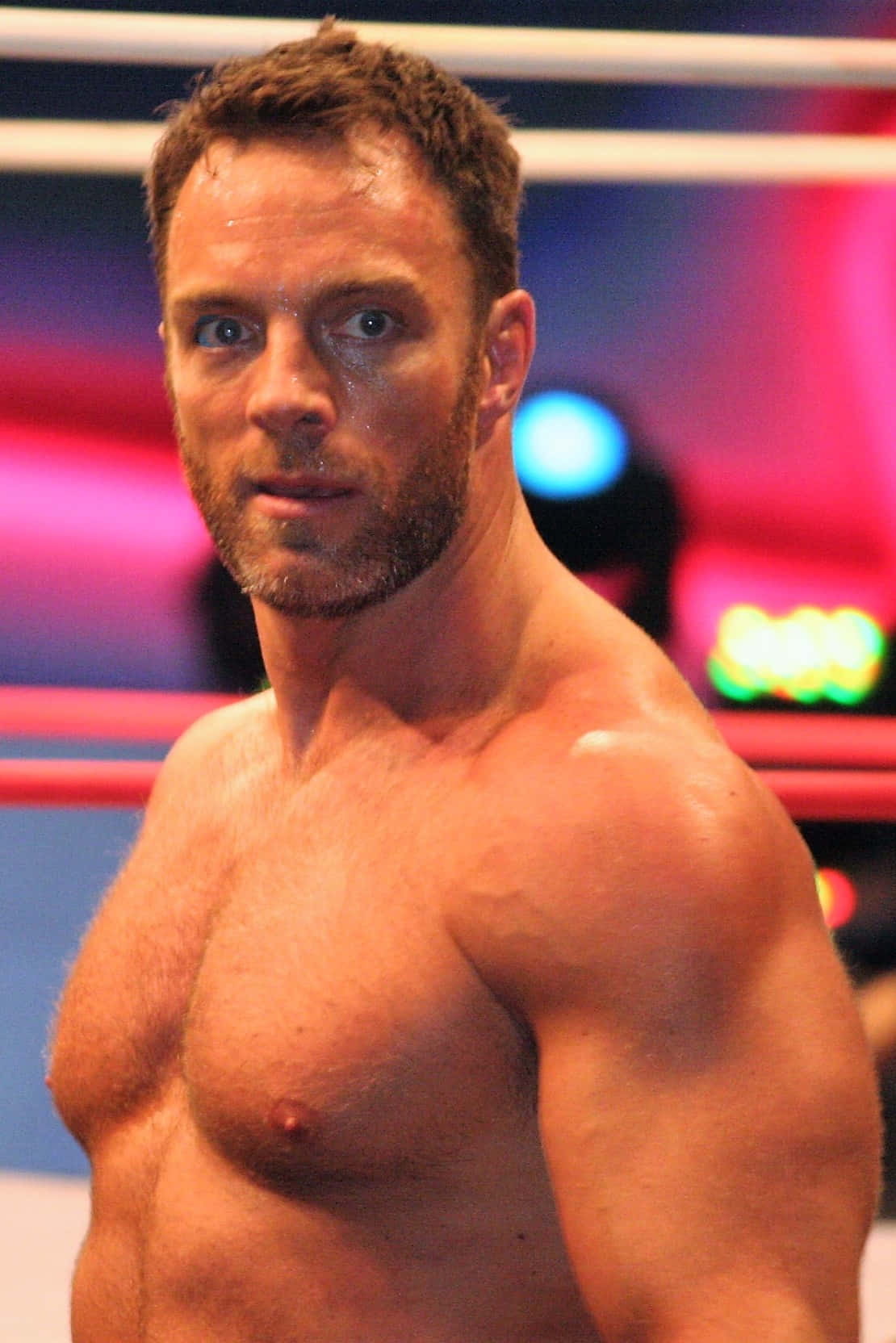 WWE 桌布 壁紙 — 一個汗流浹背的肌肉男在燈光璀璨的摔角擂台上凝視前方。