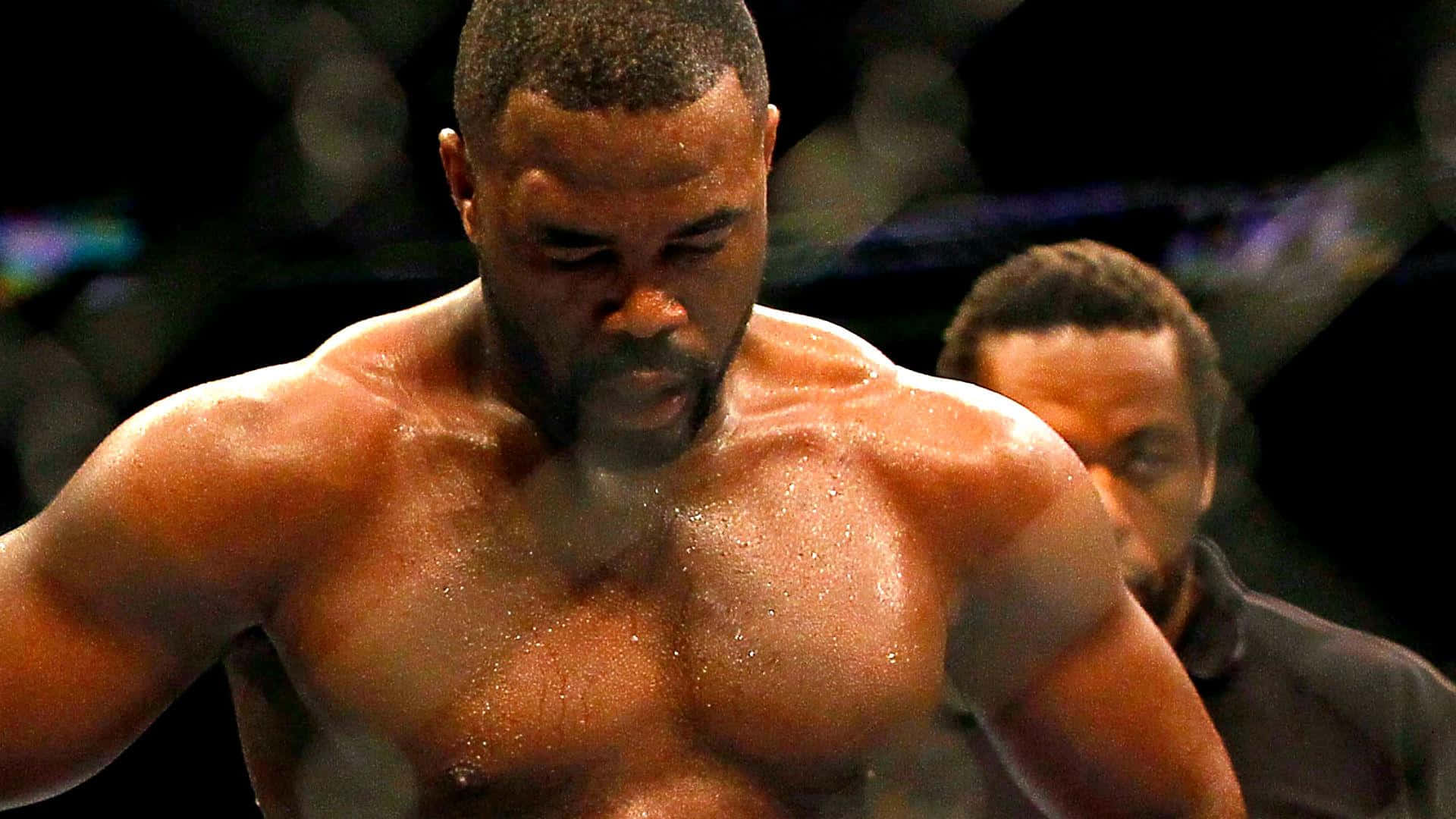 UFC 桌布 壁紙 — 一個汗流浹背的肌肉發達拳擊手在明亮的場館燈光下於擂台上痛苦地扭曲表情。
