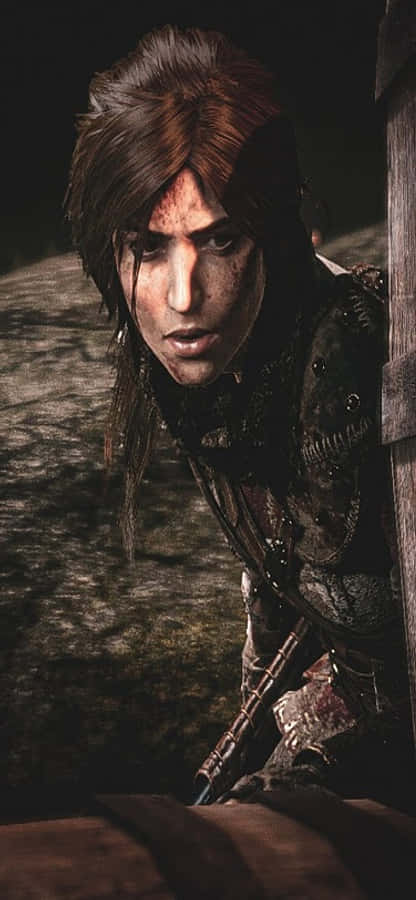 iPhone X Shadow Of The Tomb Raider 桌布 壁紙 — 一個決心堅定的戰士，臉上沾滿污垢，身穿破爛盔甲，蹲伏在陰暗廢墟中的粗獷特寫。