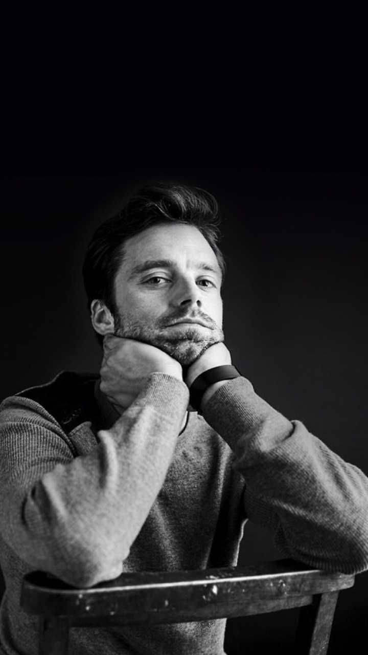 Sebastian 桌布 壁紙 — 一個沉思中的男人穿著毛衣，雙手托腮，背景是純黑色。