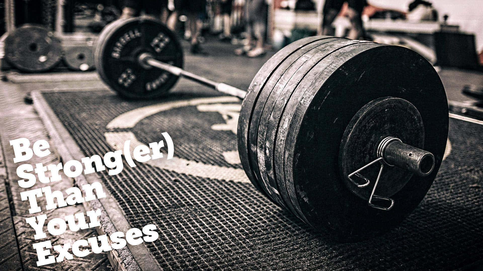 Barbell 桌布 壁紙 — 一個沉重的槓鈴放在健身房地板上，圖像上覆蓋著勵志文字。