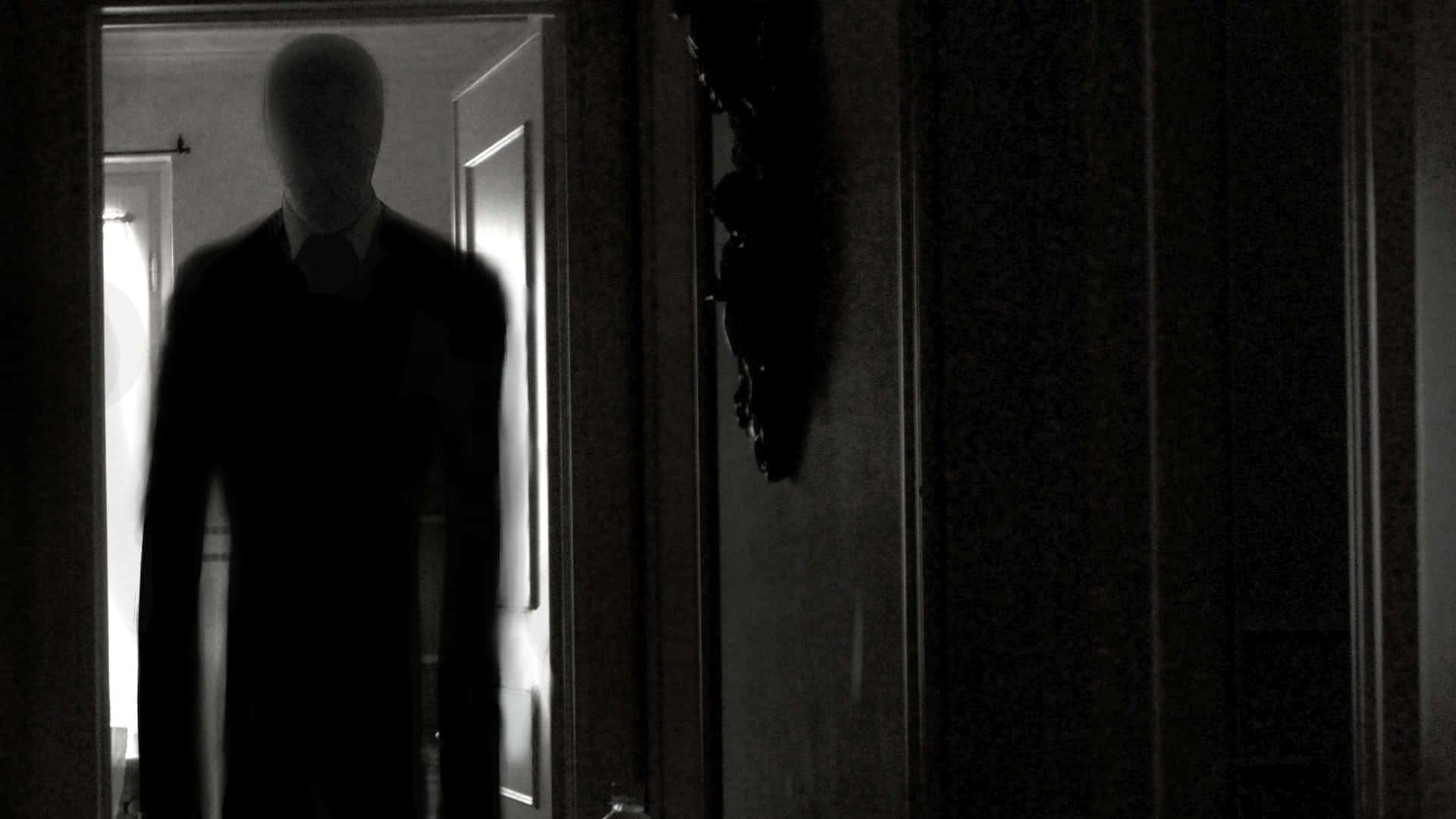 Creepypasta 桌布 壁紙 — 一個沒有面孔的陰影人形身影站在昏暗的門口，投射出詭異的剪影。
