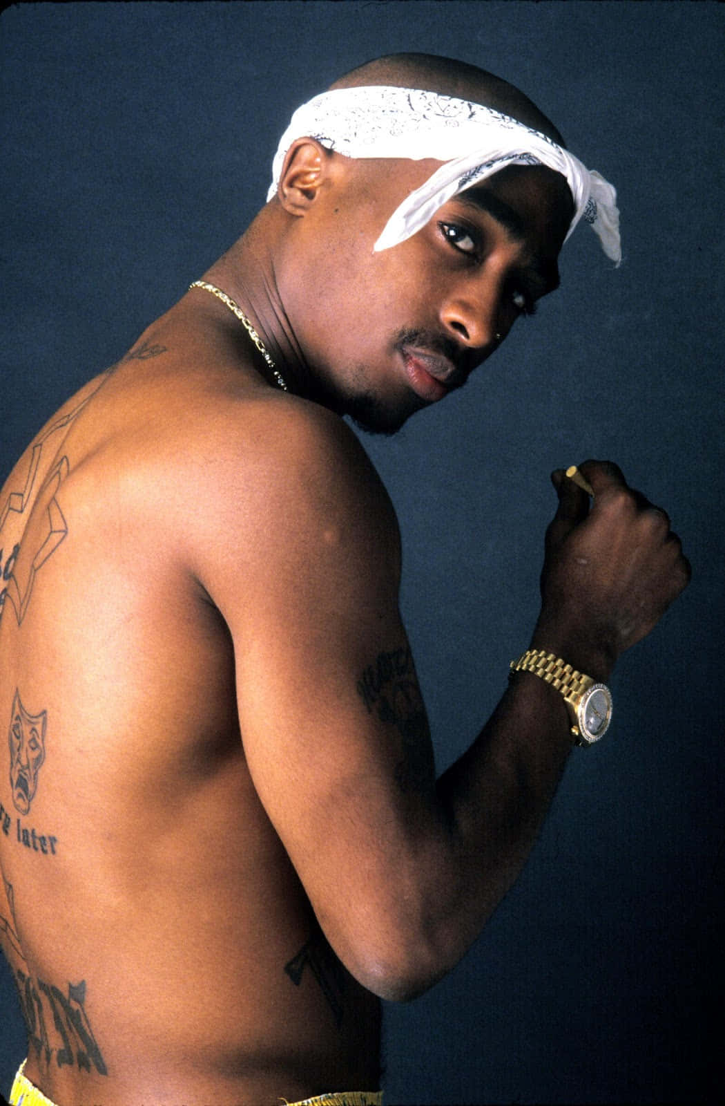 一個刺青男人戴著白色頭巾和金錶，在工作室肖像中擺姿勢。 — Tupac GIF 壁紙