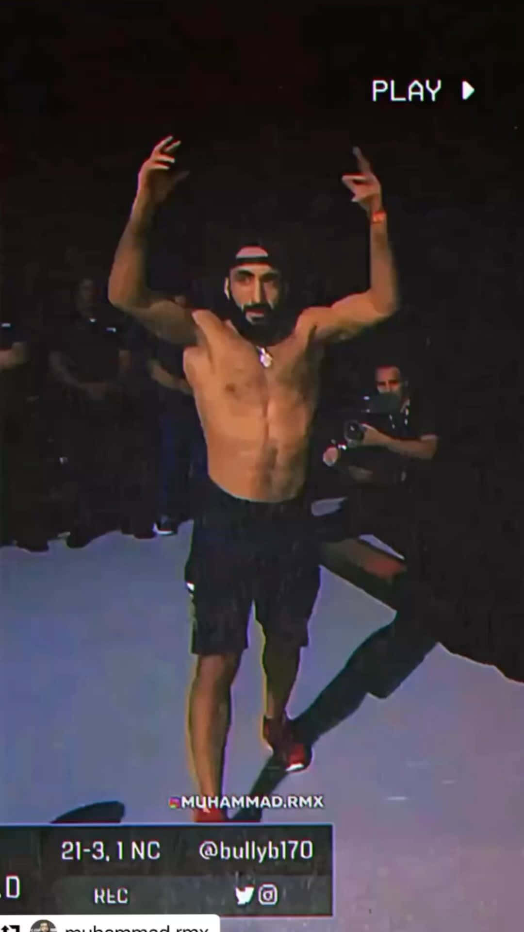MMA 桌布 壁紙 — 一個沒穿上衣的男人，留鬍子戴帽子，在燈光昏暗的運動場上高舉雙臂慶祝勝利。