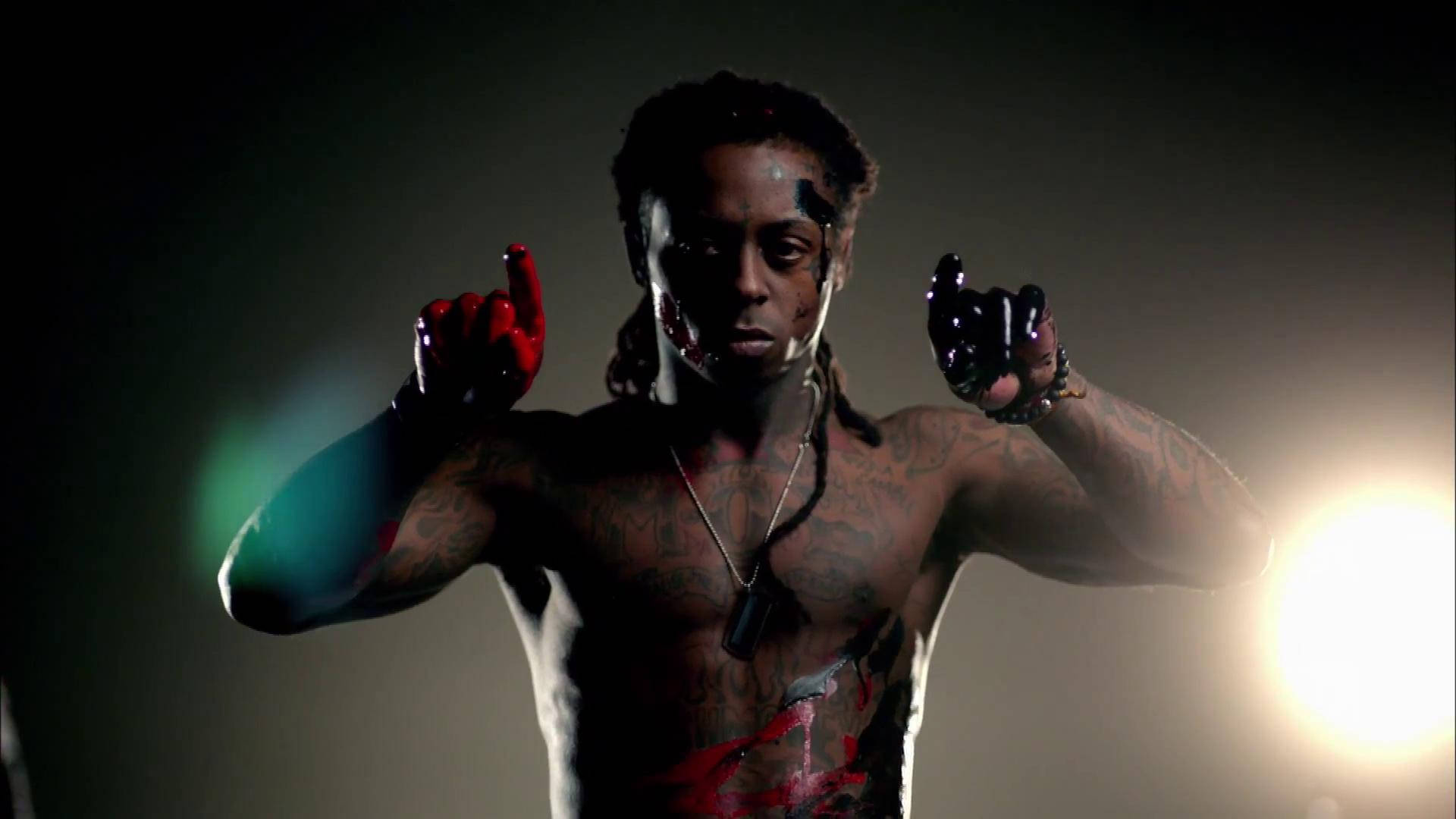 Lil Wayne 桌布 壁紙 — 一個沒穿上衣的男人，身上有刺青和血跡，在戲劇性的工作室燈光下，用兩隻食指指向前方。