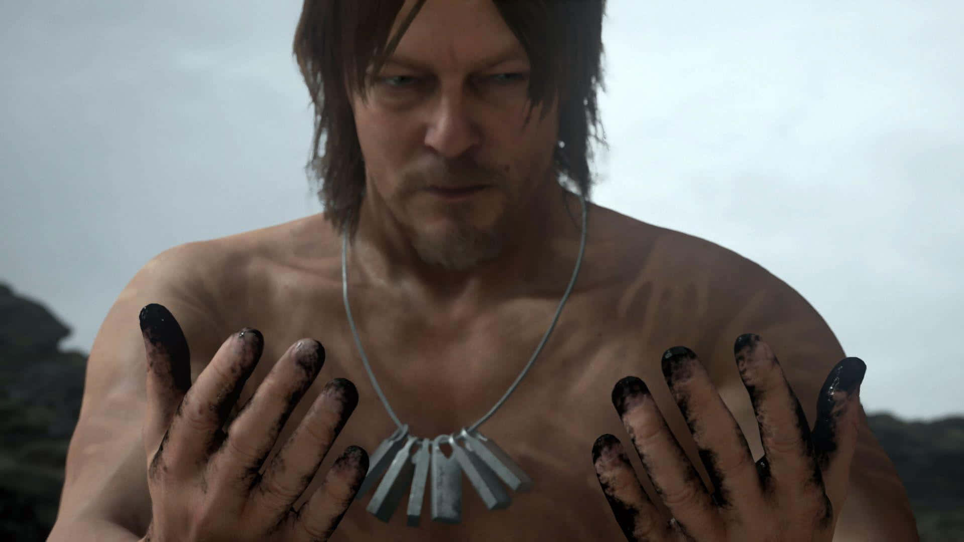 Death Stranding Desktop 桌布 壁紙 — 一個沒穿上衣的男人，髒手和金屬吊墜，在多雲的戶外背景下強烈地凝視著。