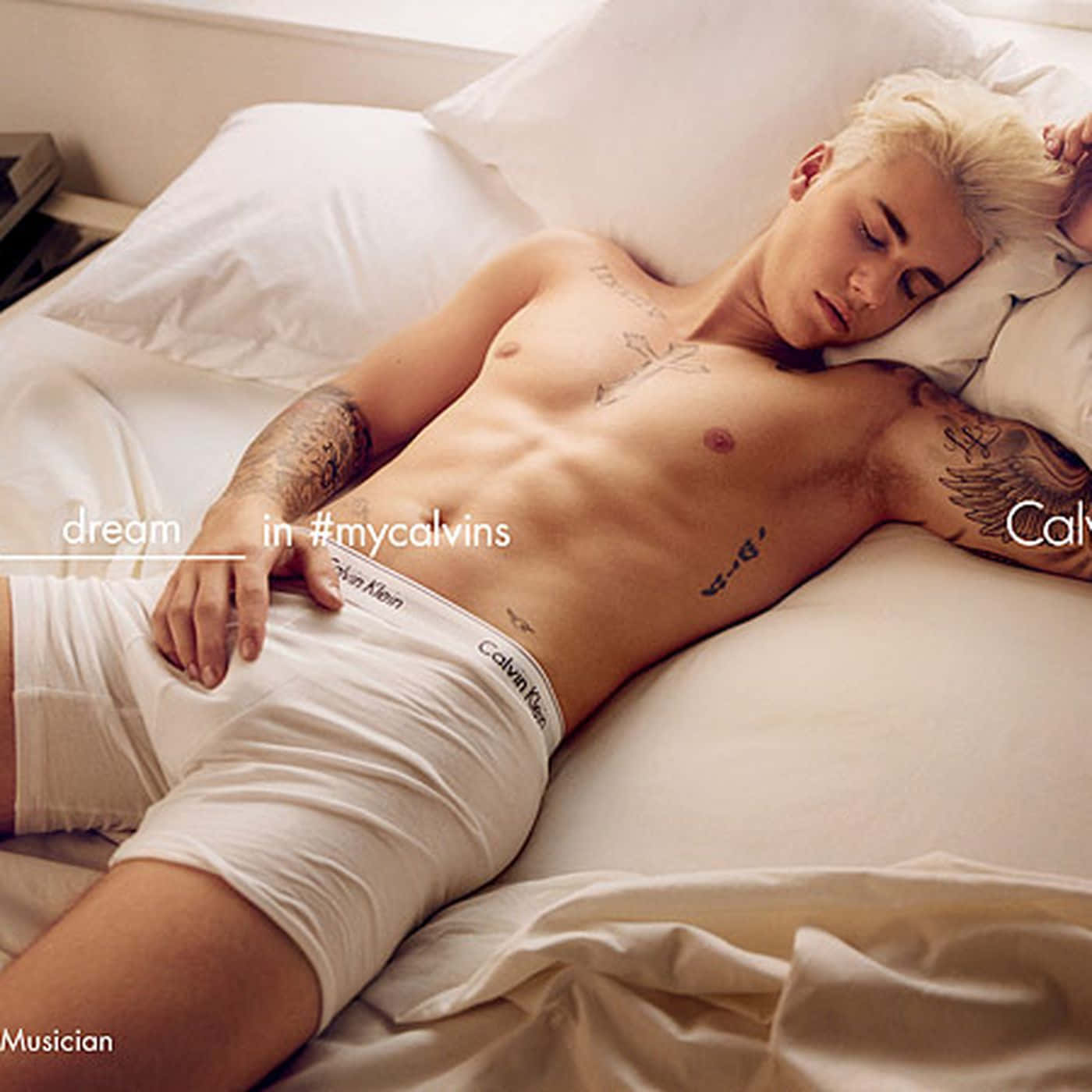 卡文克萊 桌布 壁紙 — 一個沒穿衣服的金髮刺青男人，穿著白色Calvin Klein內褲，在床上安眠。