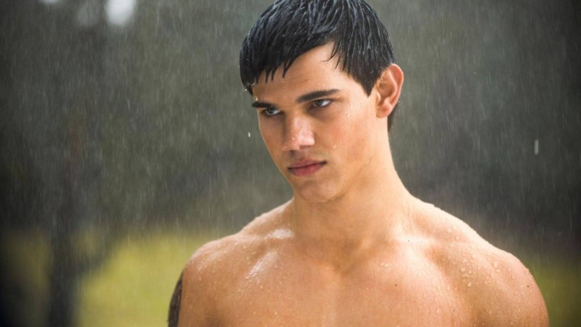 Taylor Lautner 桌布 壁紙 — 一個沒穿襯衫的年輕男子，濕透的黑髮，站在大雨中，專注地看著鏡頭。