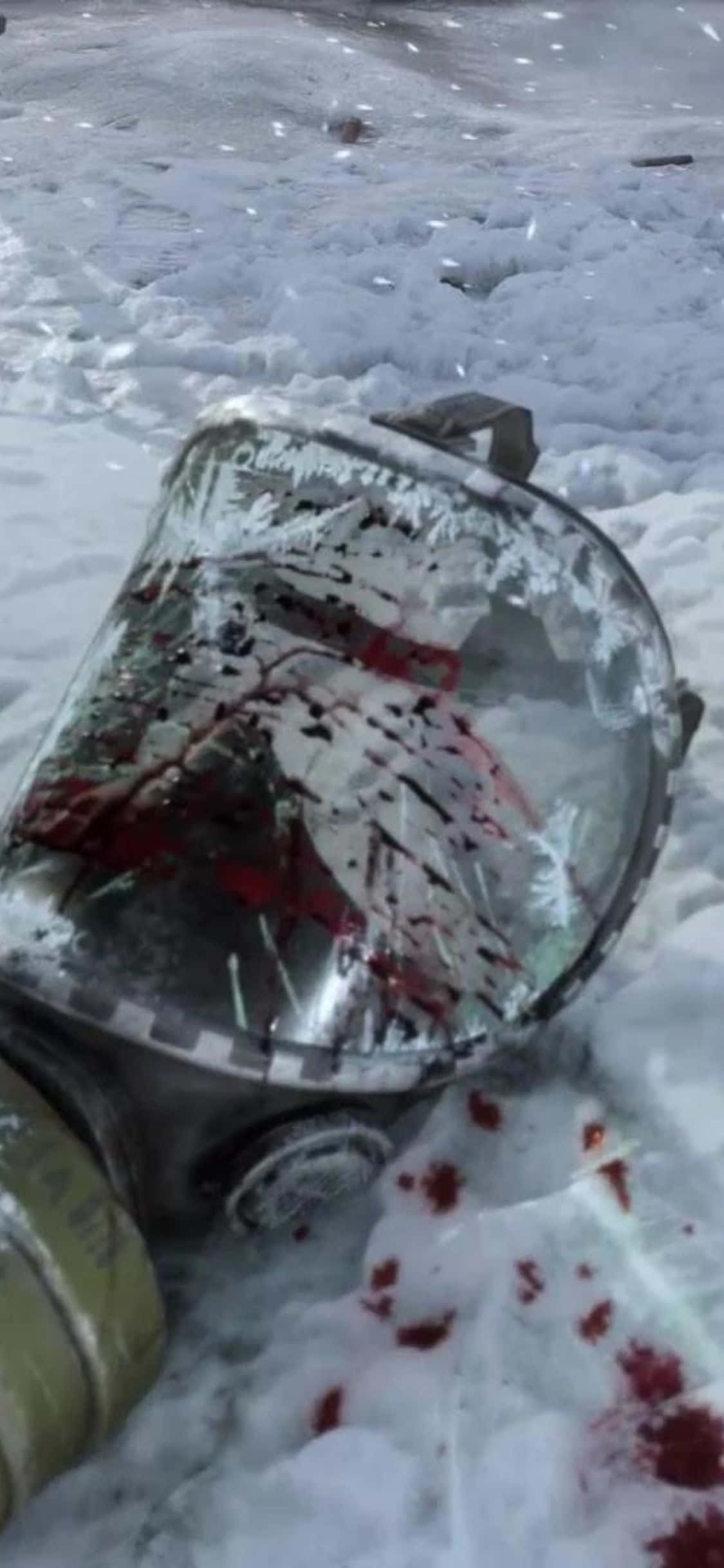 iPhone X Metro Exodus 桌布 壁紙 — 一個沾滿血跡的防毒面具被遺棄在深雪中，面罩破裂並染有鮮紅色的條紋。