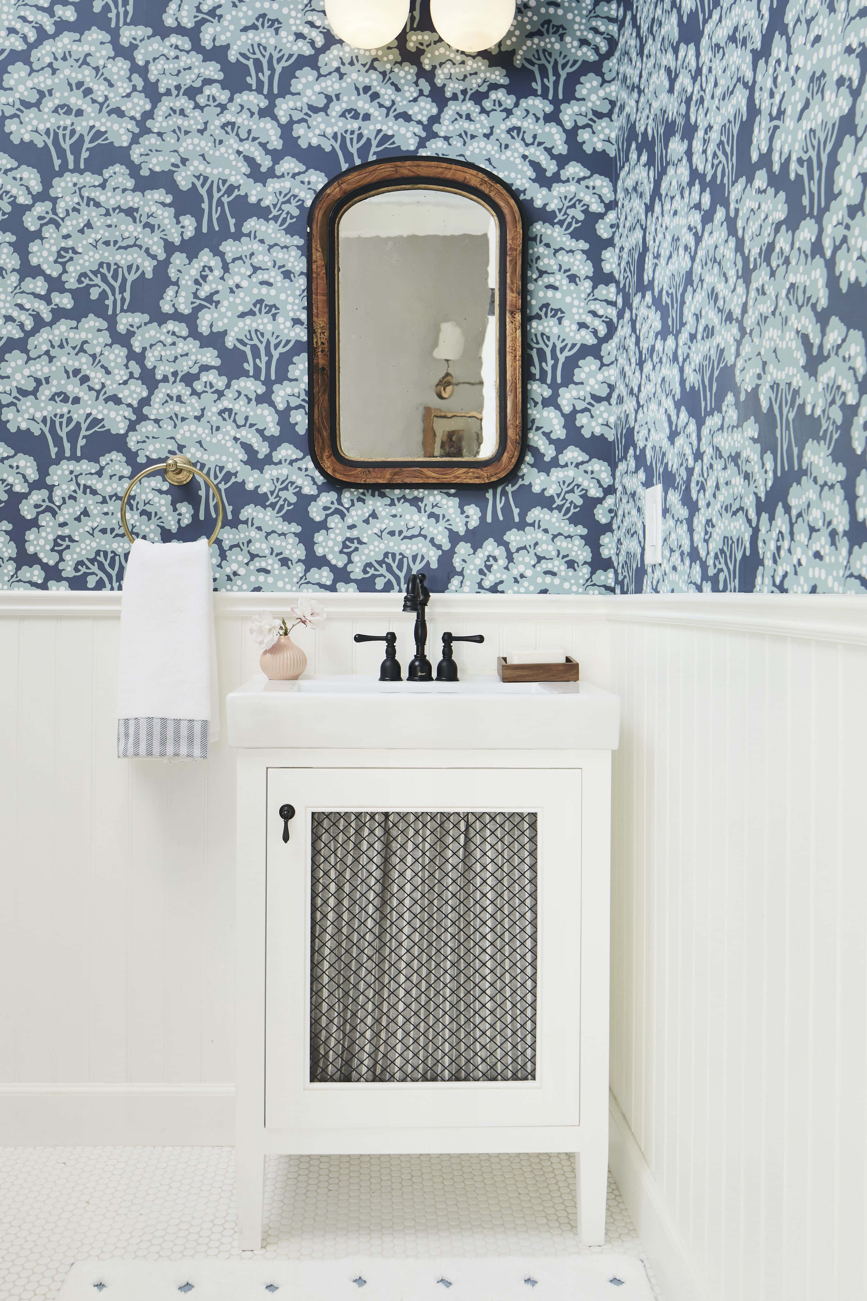 Bathroom Decor 桌布 壁紙 — 一個浴室，配有藍色樹紋壁紙、白色護牆板、復古鏡子，以及帶黑色配件的白色梳妝台。