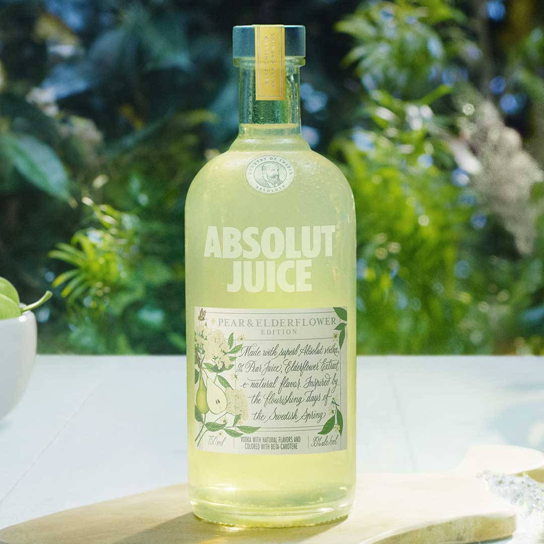 一個梨和接骨木花味伏特加瓶放在花園環境中的木板上。 — Juice Wrld 壁紙