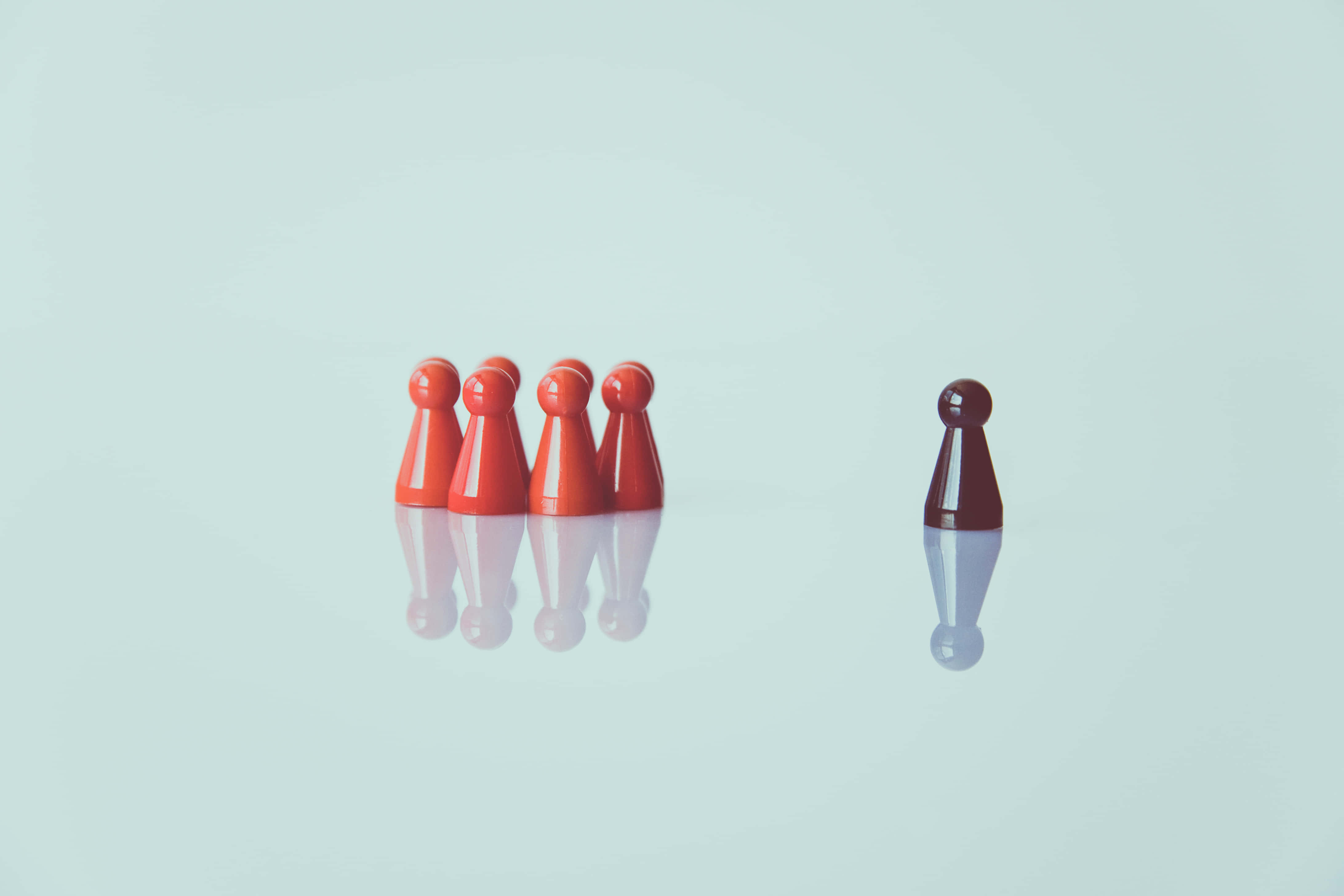 Racism 桌布 壁紙 — 一個深紅色遊戲棋子與四個紅色棋子分開，立於淺藍色反光表面上。