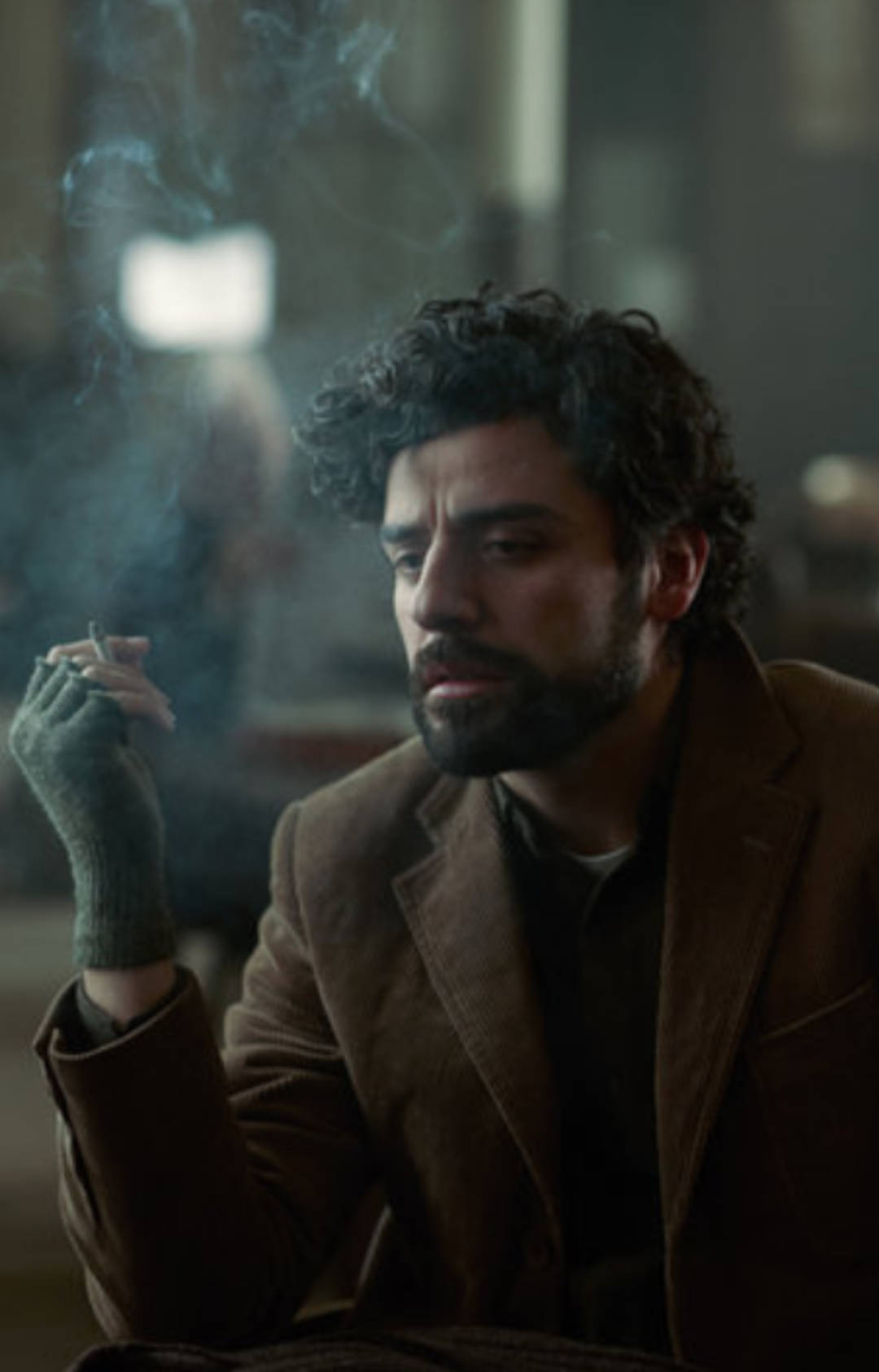 inside llewyn davis 桌布 壁紙 — 一個深色捲髮和鬍鬚的男人在昏暗的房間裡抽煙，煙霧向上繚繞。