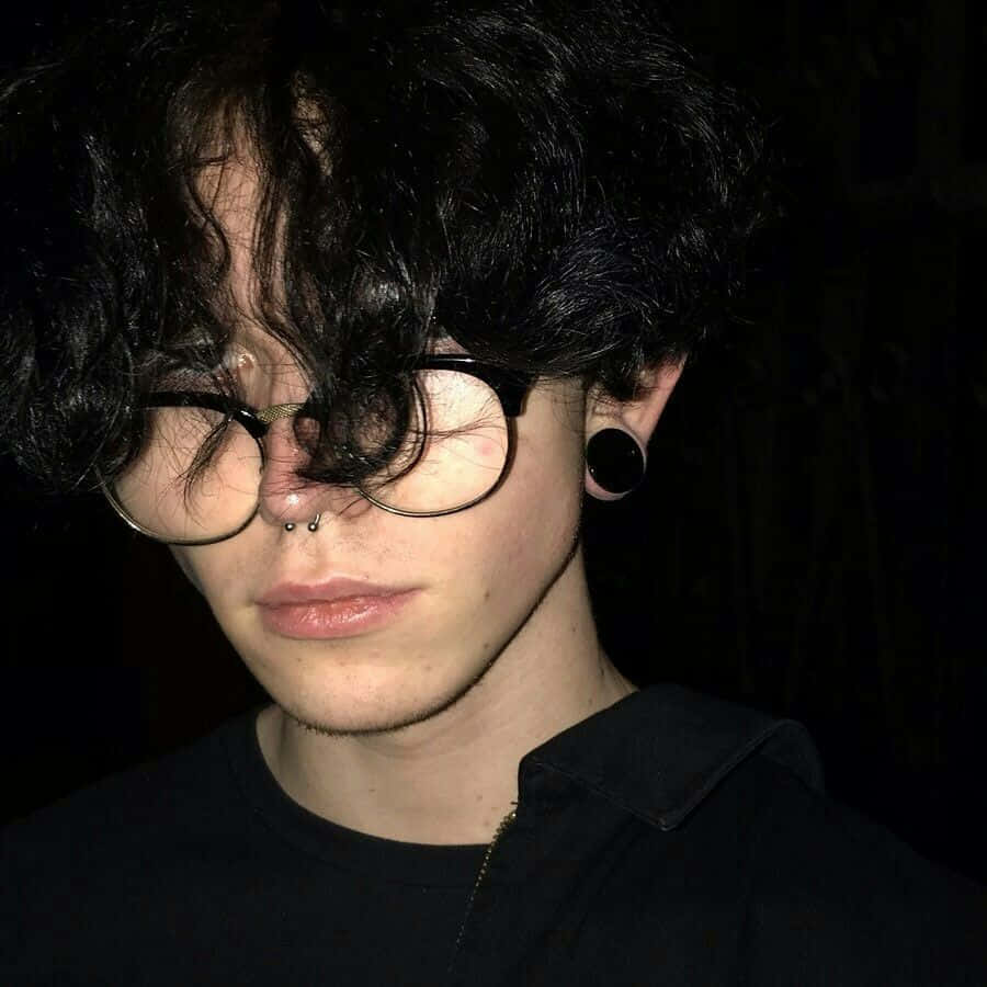 emo 美學 桌布 壁紙 — 一個深色捲髮戴眼鏡的人，在黑色背景前部分遮蓋臉部。