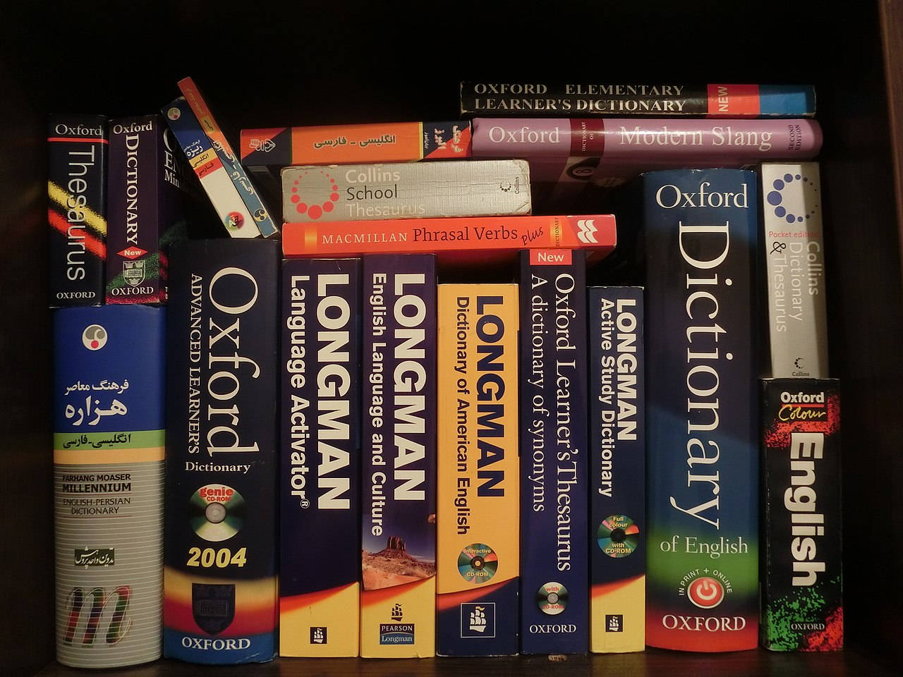 Dictionary 桌布 壁紙 — 一個深色木書架的近距離特寫，裡面裝滿了色彩繽紛的英語學習詞典和參考書。