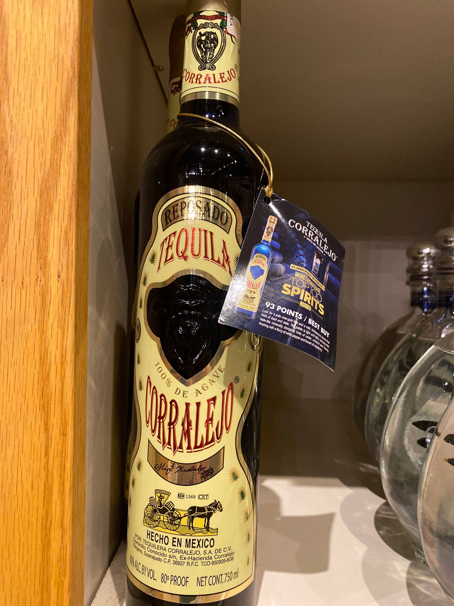 Drink 桌布 壁紙 — 一個深色玻璃瓶的Corralejo Reposado龍舌蘭酒，帶有金色標籤，放在架子上，旁邊有其他瓶子。