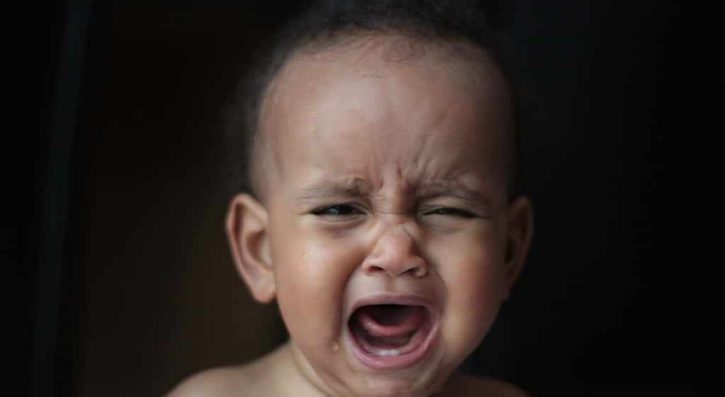 cry 桌布 壁紙 — 一個深色皮膚的嬰兒在黑色背景前激烈哭泣的特寫。