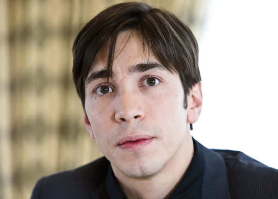 Justin Long 桌布 壁紙 — 一個深色頭髮、眼神強烈的棕色眼睛男子近距離肖像，直接望向鏡頭，身穿深色西裝。