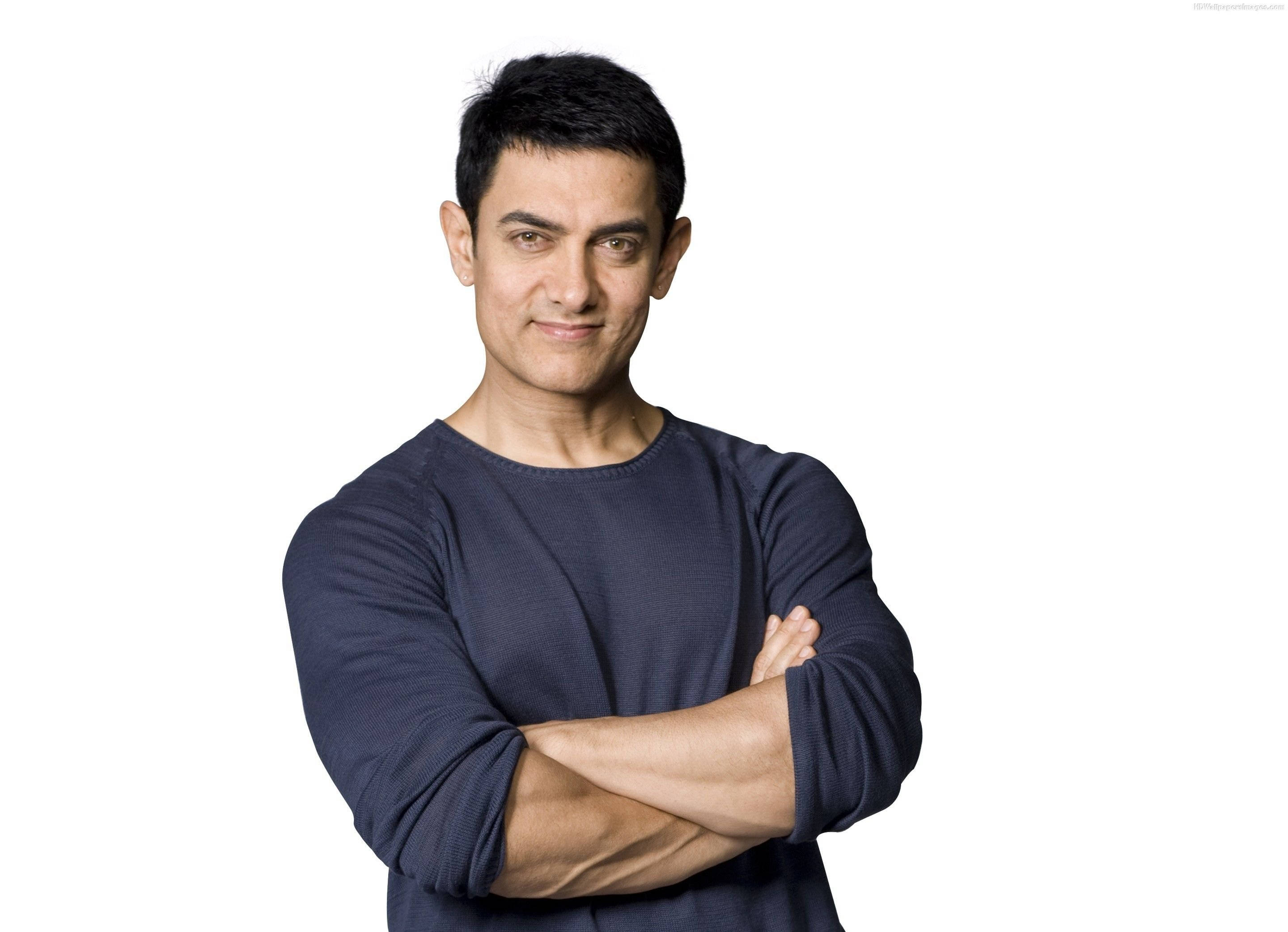 Aamir Khan 桌布 壁紙 — 一個深色頭髮、自信微笑的男人，雙臂交叉，站在純白色背景前，穿著深藍色長袖襯衫。
