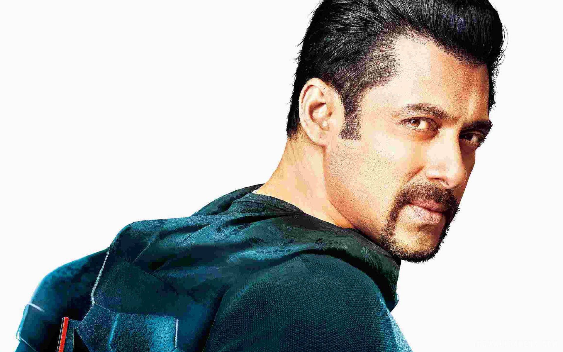 salman khan HD 桌布 壁紙 — 一個深色頭髮和山羊鬍的男人，穿著深色連帽衫，在白色背景上轉頭越過肩膀。