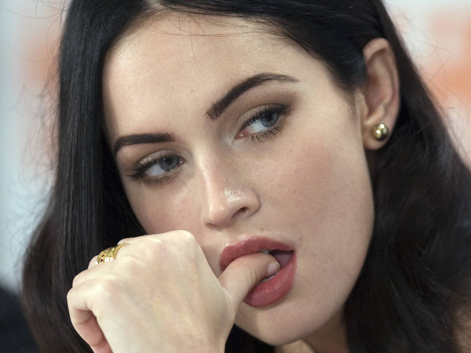 Megan Fox HD 桌布 壁紙 — 一個深色頭髮和紅唇的女人咬著手指，同時看向別處的特寫肖像。