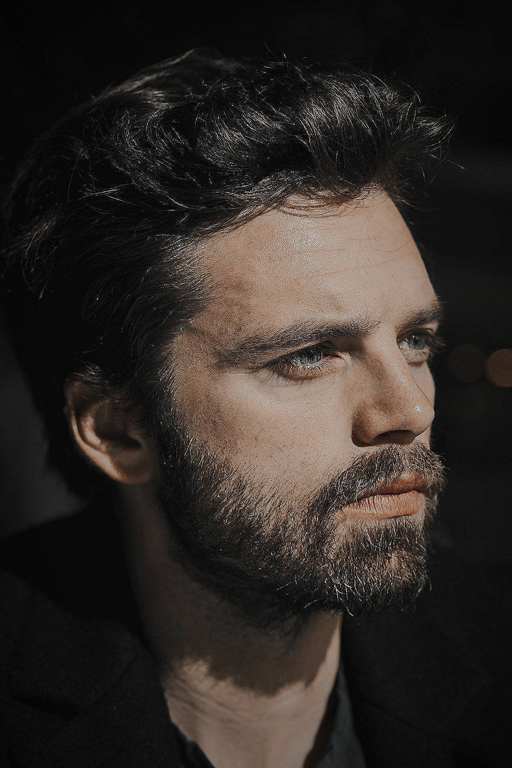 Sebastian 桌布 壁紙 — 一個深色頭髮和鬍鬚的男人在柔和的側光下，對著黑暗的背景沉思地凝視。