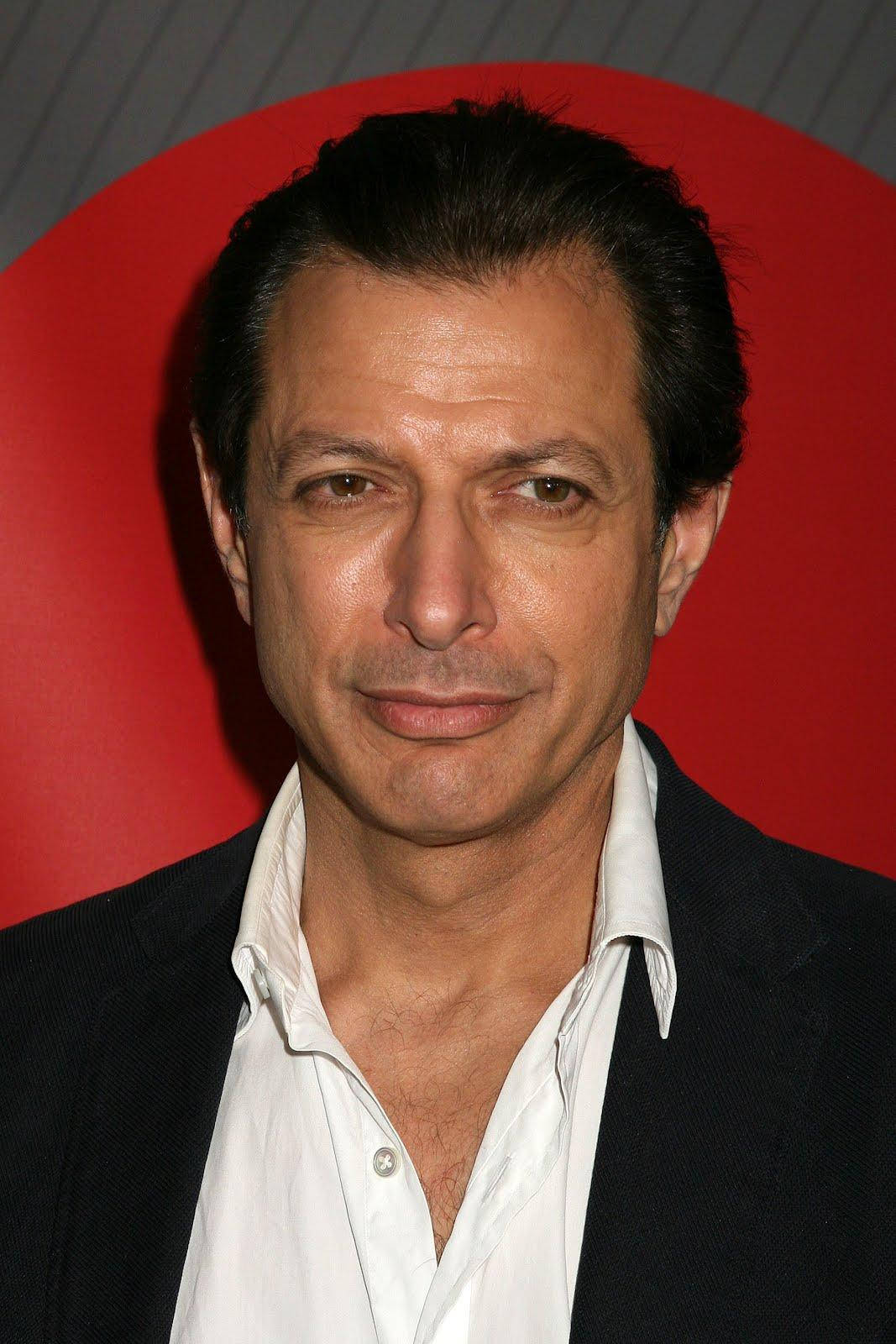 Celebrity 桌布 壁紙 — 一個深色頭髮男士的特寫肖像，在鮮明的紅色圓形背景前露出含蓄的微笑。