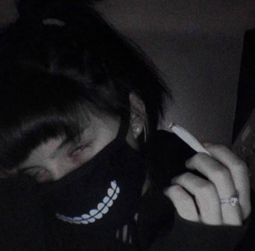 Monochrome 桌布 壁紙 — 一個深色頭髮的人，在昏暗燈光下戴著一個帶有白色葉子圖案的黑色面具，部分遮蓋了臉部。
