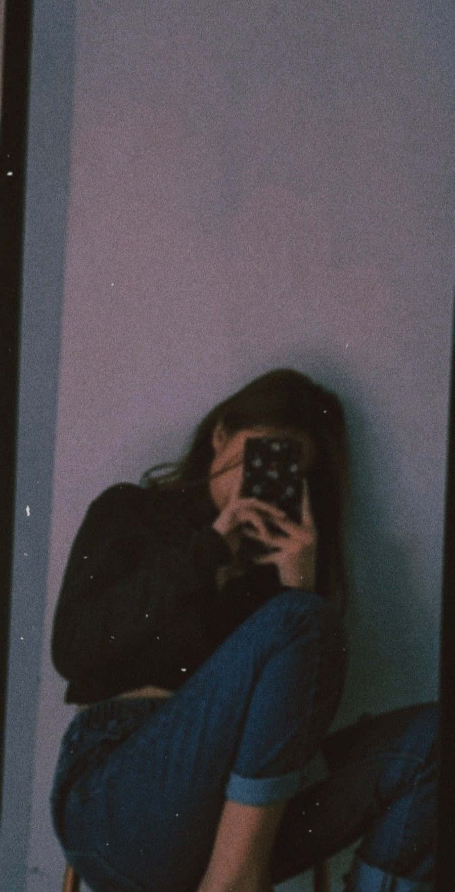 女孩 桌布 壁紙 — 一個深色頭髮的人靠著淺色牆壁，在昏暗的房間裡，紫色環境光下，將手機貼在臉上。