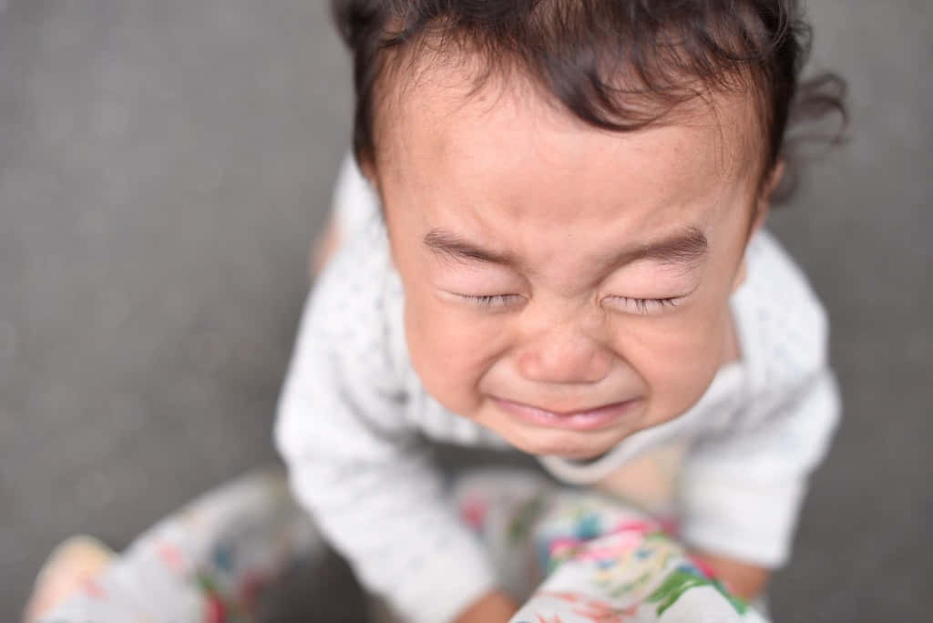cry 桌布 壁紙 — 一個深色頭髮的嬰兒閉緊雙眼、嘴角下垂，正在激烈哭泣的特寫。