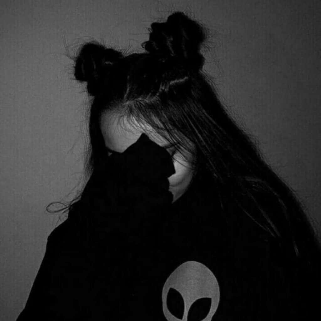 Sad Profile 桌布 壁紙 — 一個深色頭髮紮成兩個髮髻的人，用一件帶有外星人標誌的黑色連帽衫遮住臉，單色。