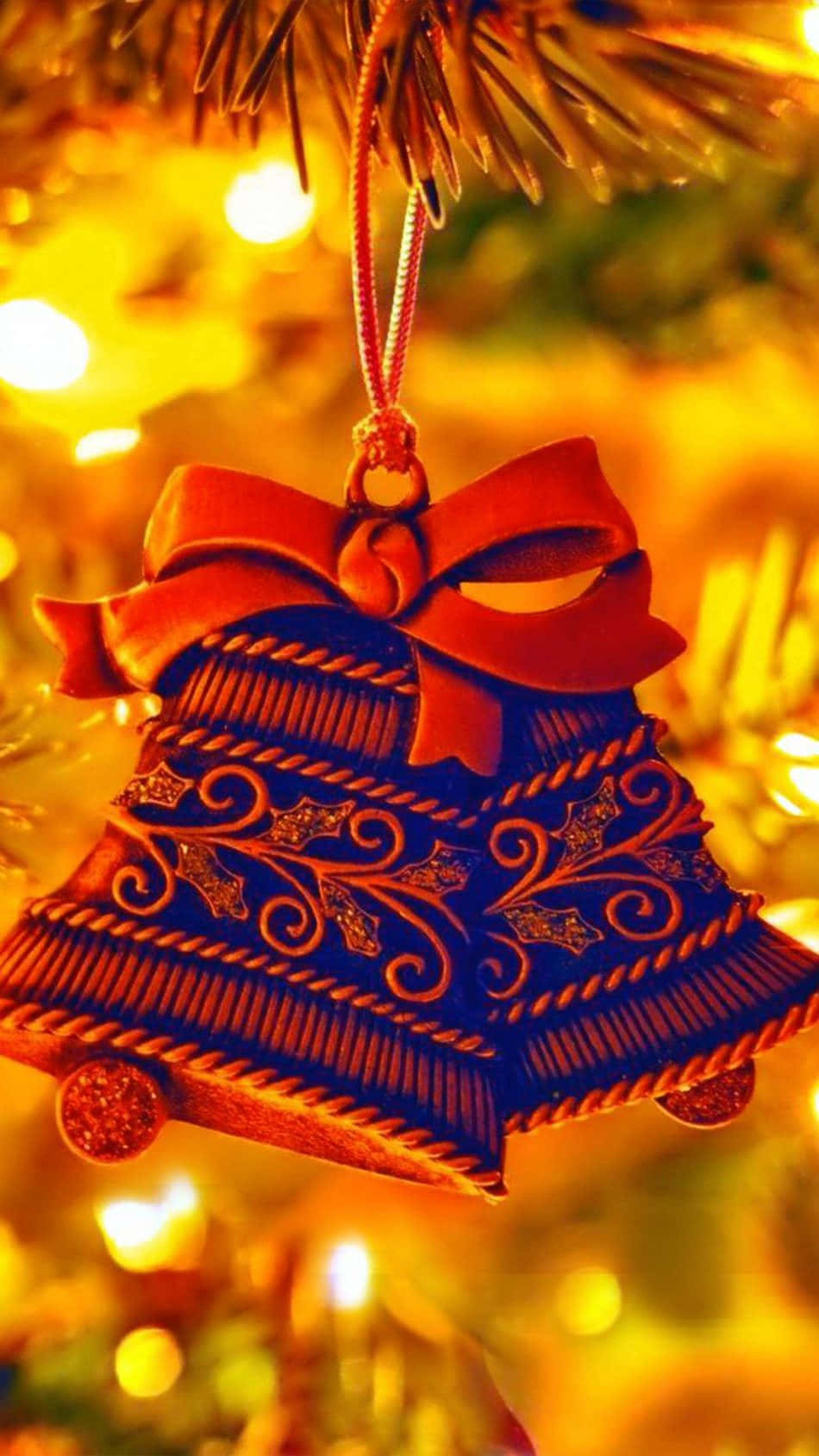 Cute Simple Christmas 桌布 壁紙 — 一個深藍色華麗鈴鐺裝飾的特寫，帶有紅色蝴蝶結，掛在松樹枝上，背景是溫暖的發光燈光。