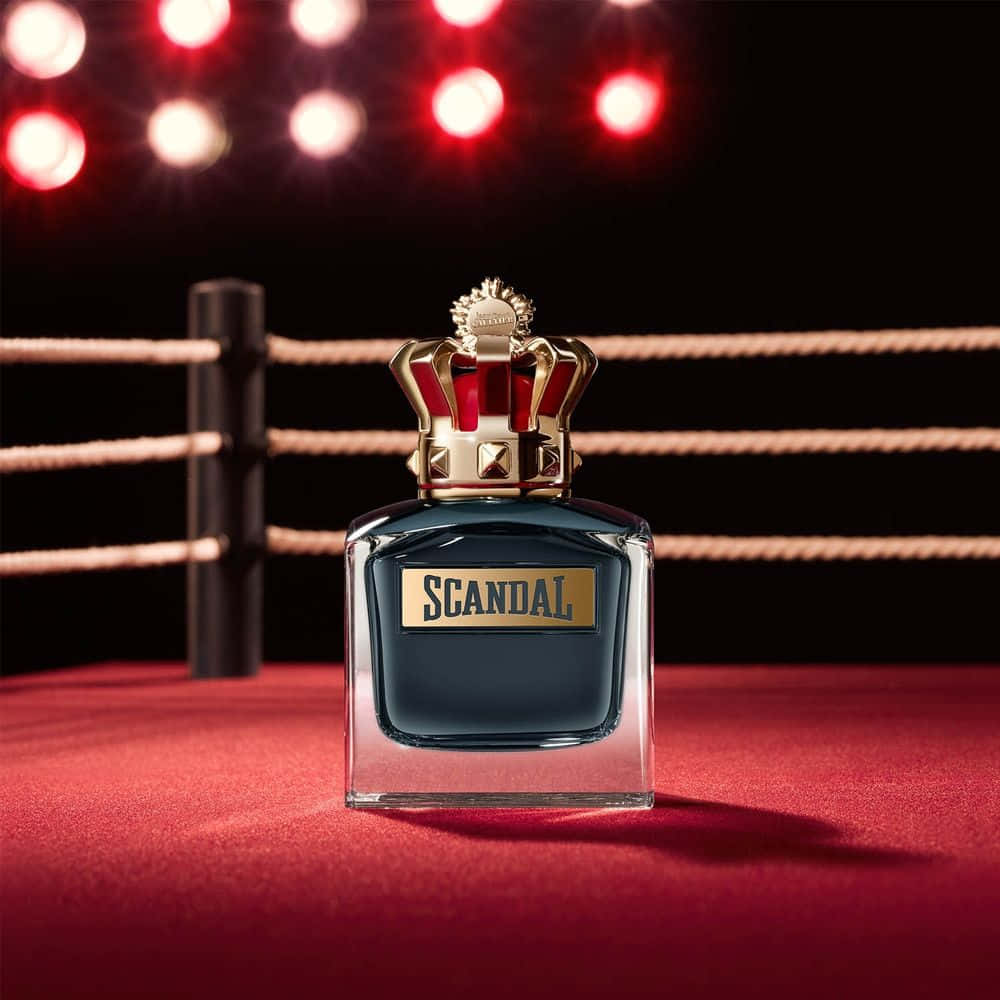 perfume 桌布 壁紙 — 一個深藍色香水瓶，帶有金色皇冠蓋，在紅色拳擊台中央，在發光的紅色聚光燈下。