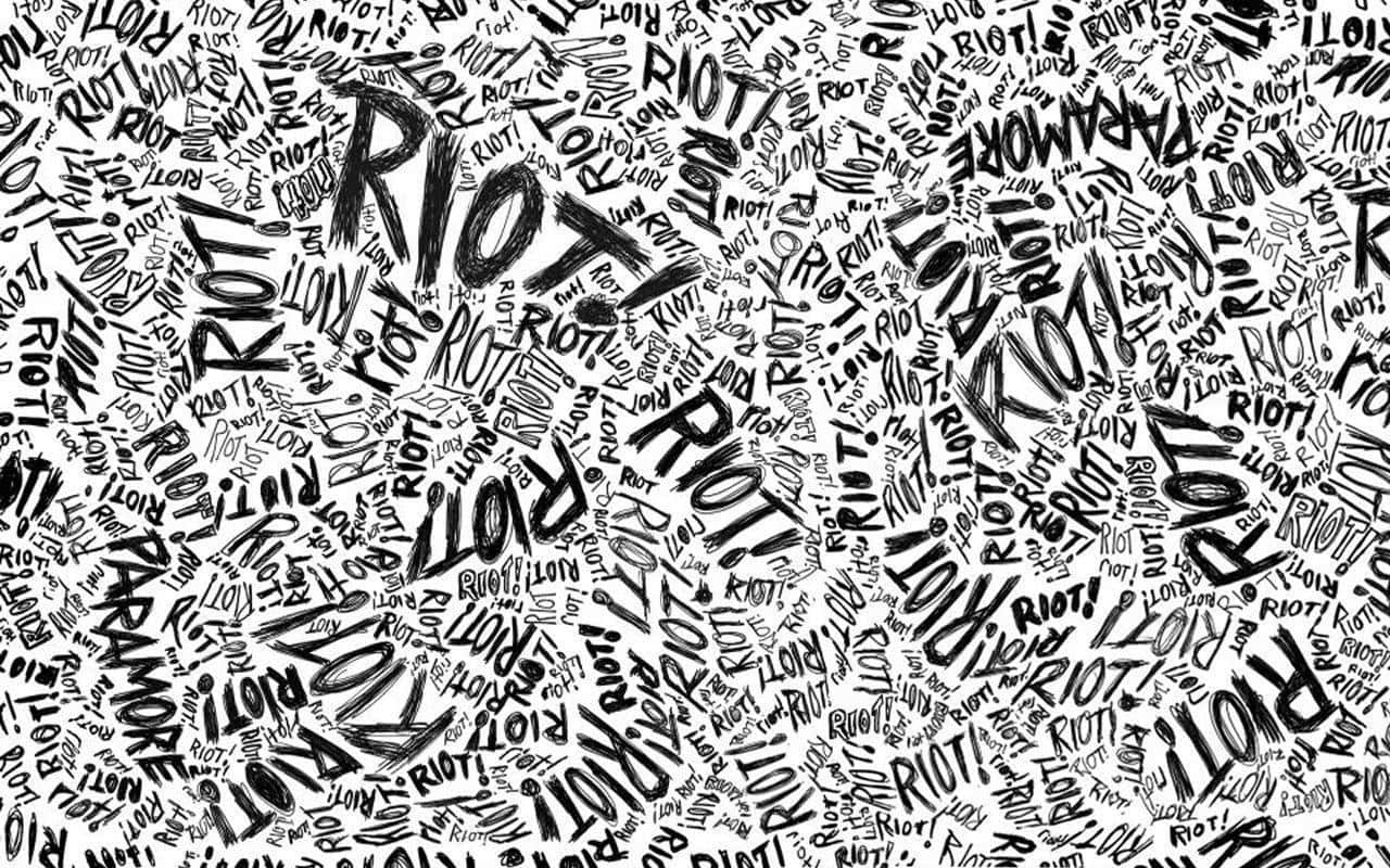 Black And White Typography 桌布 壁紙 — 一個混亂的黑白桌布，充滿了像 'RIOT' 和 'PARA MORE' 這樣旋轉的手寫字，採用大膽的塗鴉風格。