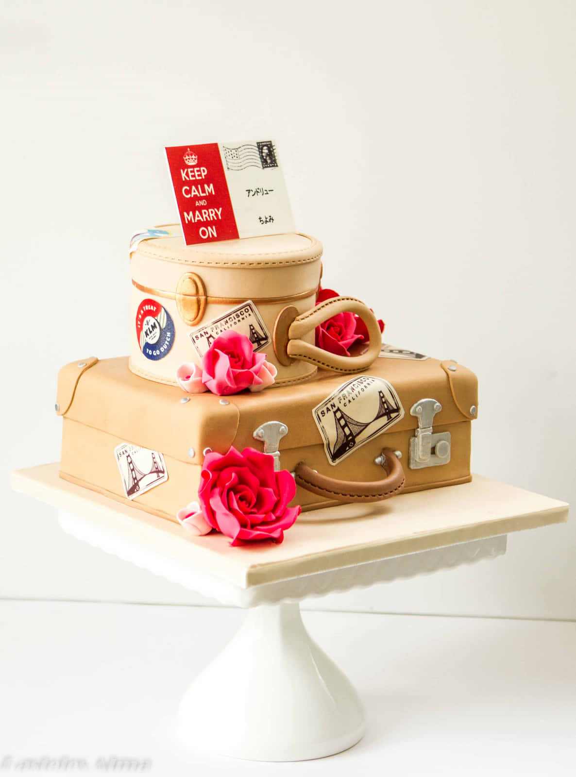 Cake Fondant 桌布 壁紙 — 一個淺棕色行李箱蛋糕，飾有旅行貼紙、玫瑰和一張「Keep Calm and Marry On」明信片，優雅地放在白色底座上。