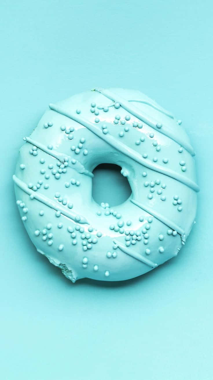 Turquoise 桌布 壁紙 — 一個淺藍色糖霜甜甜圈配上相配的彩色糖粒，居中放置在純青色背景上。