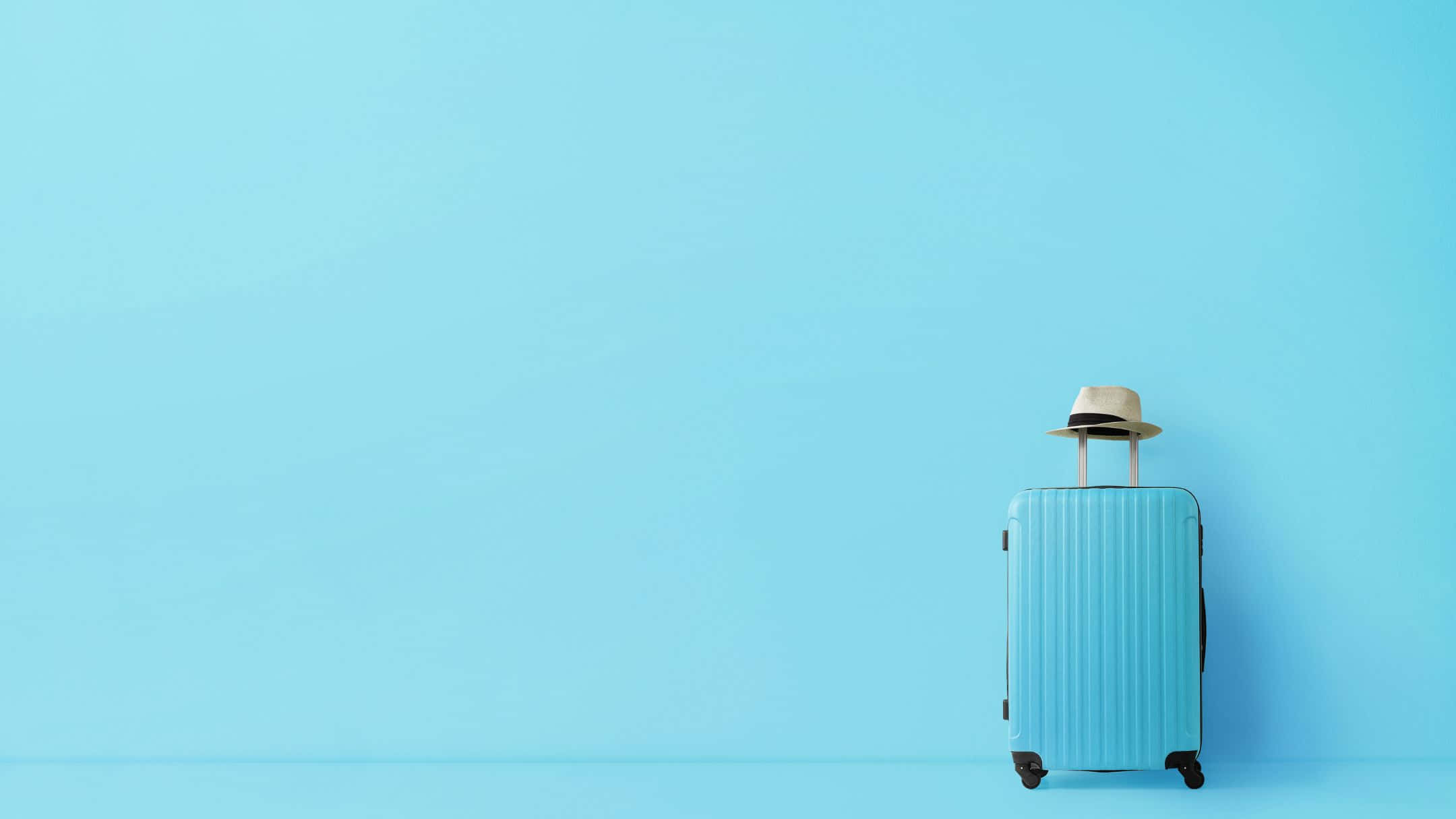 Traveling 桌布 壁紙 — 一個淺藍色行李箱，手柄上放著一頂草帽，獨自立在純藍色背景前。