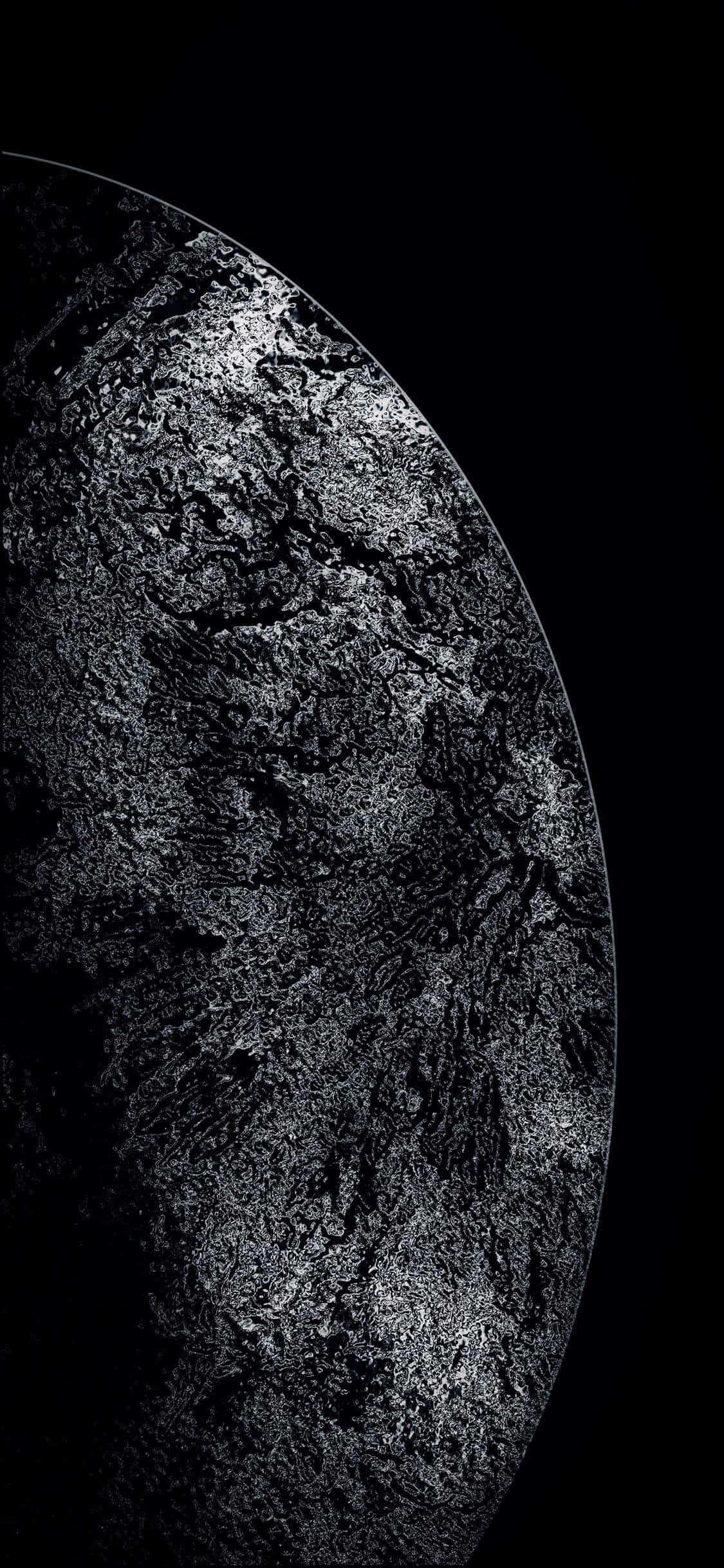 Black Shiny 桌布 壁紙 — 一個清晰的近距離鏡頭，顯示佈滿隕石坑的月球表面，在漆黑虛空中微微發光。
