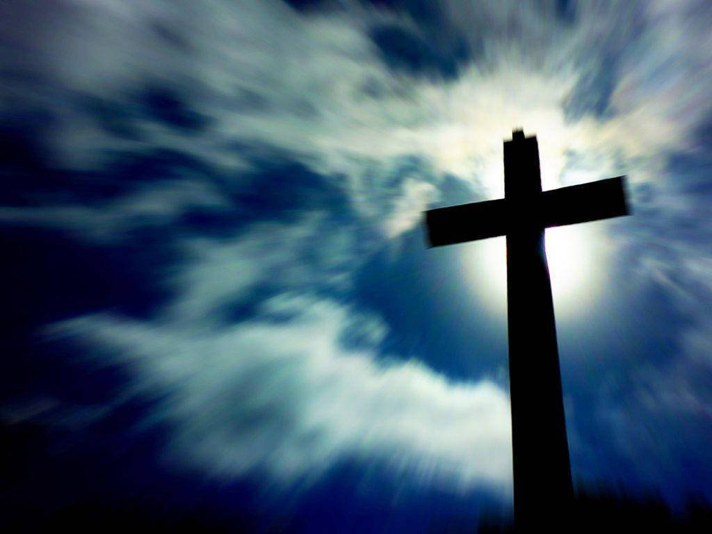 god laptop 桌布 壁紙 — 一個清晰的黑色十字架剪影，矗立在旋轉的藍白雲天背景下，背後有耀眼的光芒迸發而出。