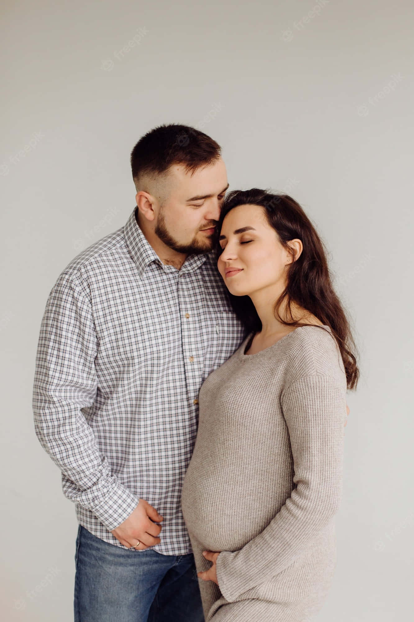 Pregnant 桌布 壁紙 — 一個溫柔的時刻，在純淺灰色背景前，伴侶輕吻孕婦的額頭。