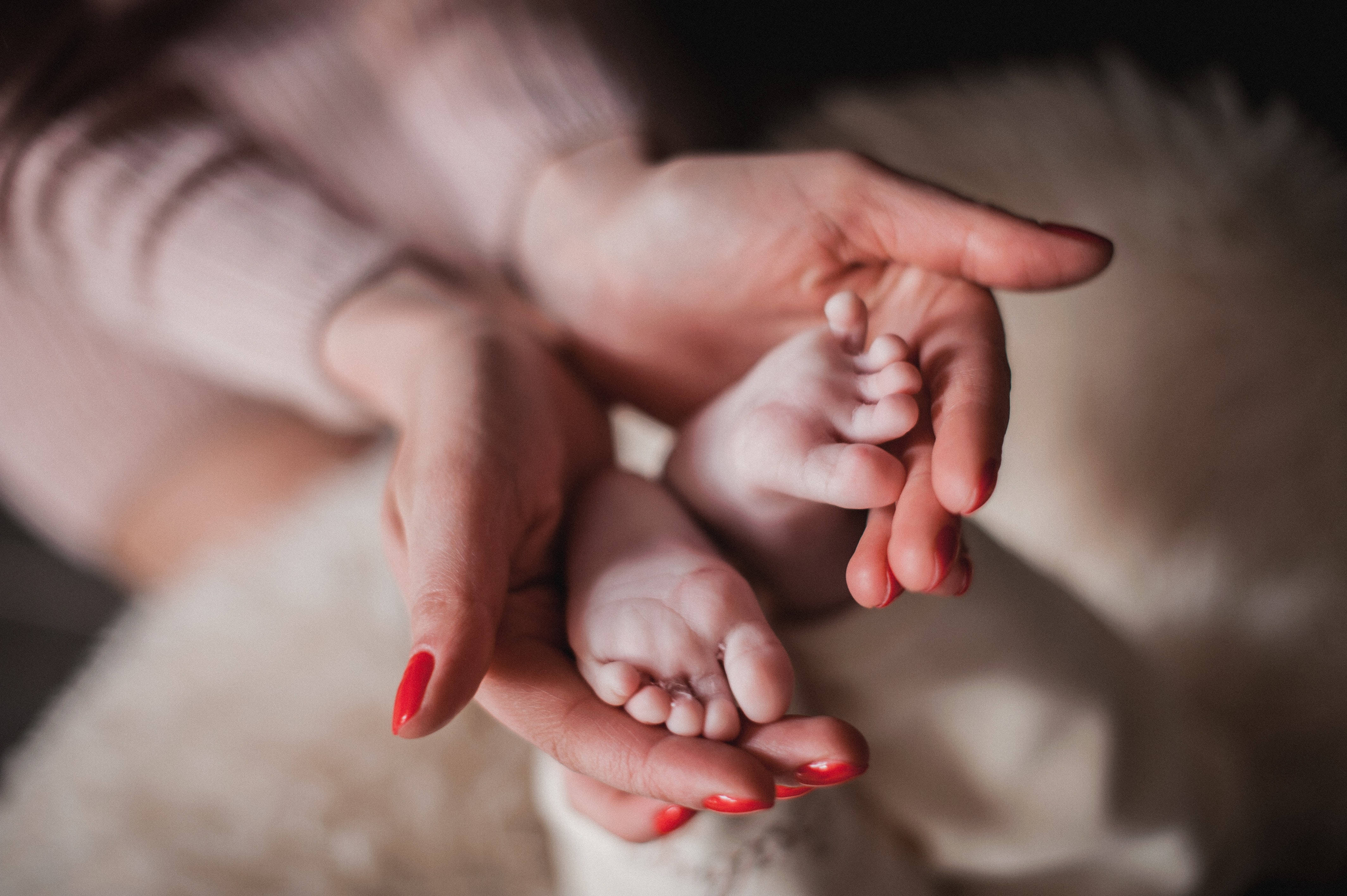 Newborn 桌布 壁紙 — 一個溫柔的特寫鏡頭，成年人的雙手在柔軟的紋理背景上托著新生兒的小腳。