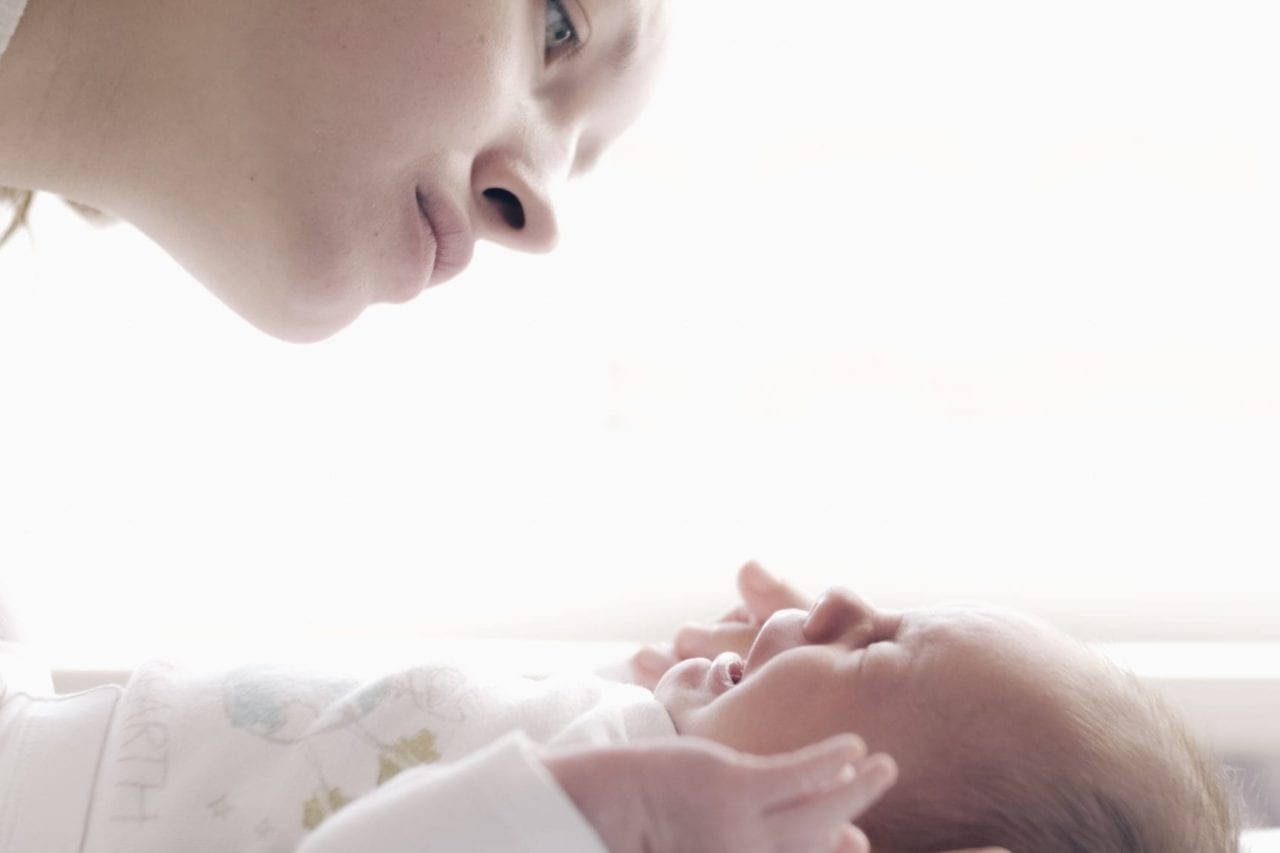 Mother And Baby 桌布 壁紙 — 一個溫柔的特寫鏡頭，母親凝視著包裹在柔和光線中的新生嬰兒。