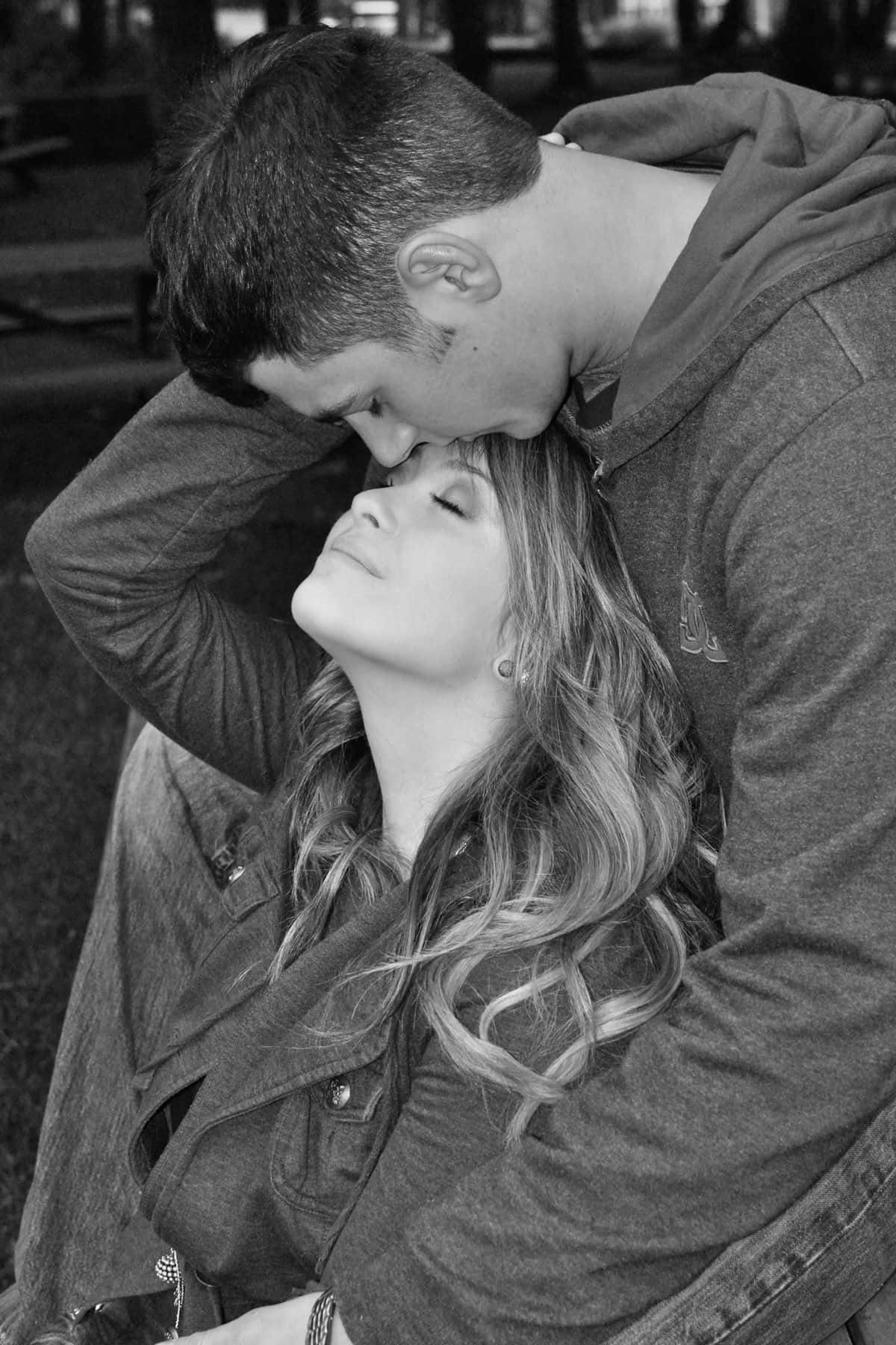 Forehead Kiss 桌布 壁紙 — 一個溫柔的黑白瞬間，一個男人輕輕親吻一個女人的額頭，而她則閉著眼睛向後靠著頭。