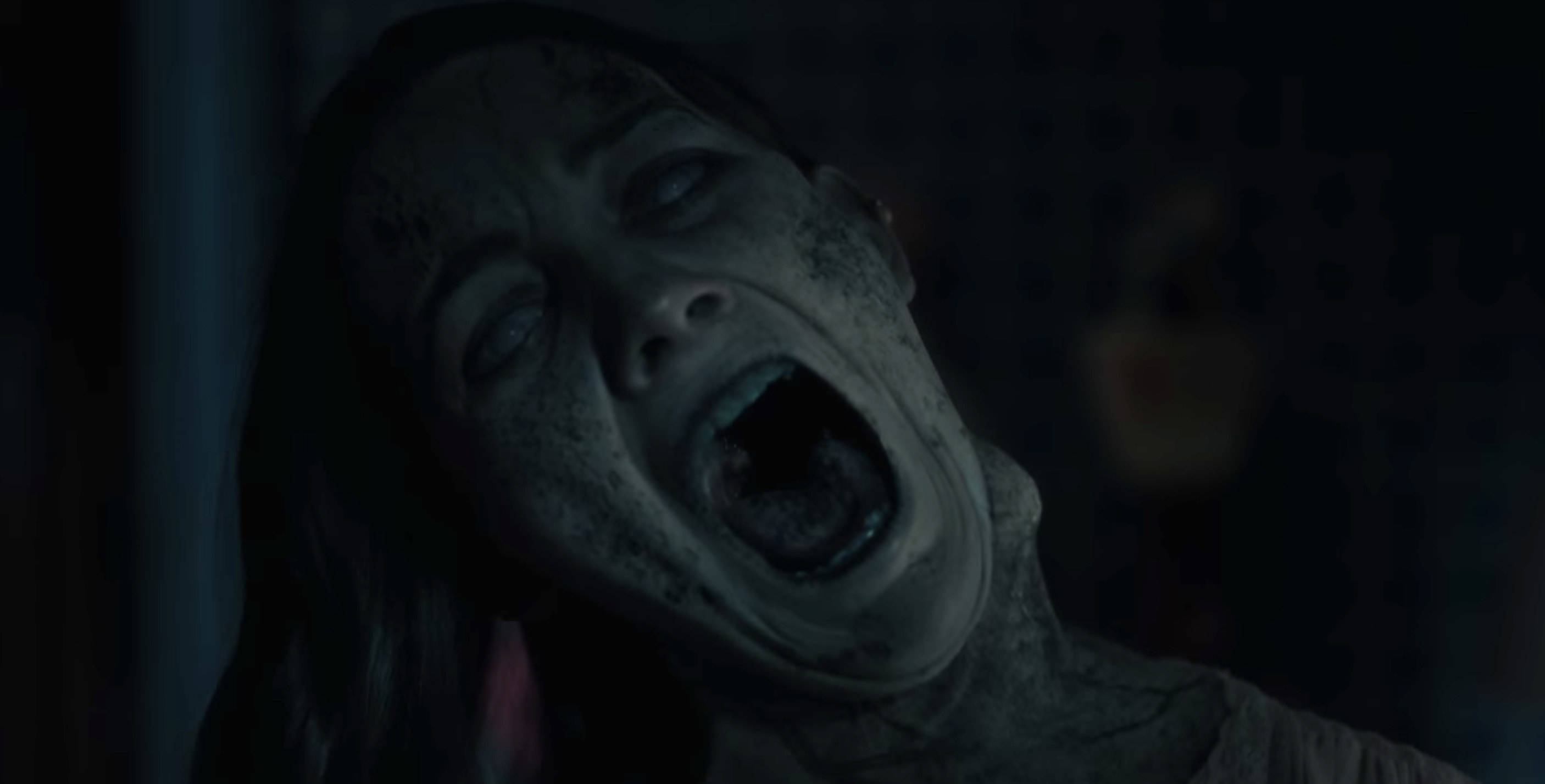 Haunting 桌布 壁紙 — 一個滿臉污垢的受驚女子在昏暗的房間裡尖叫，背景模糊。